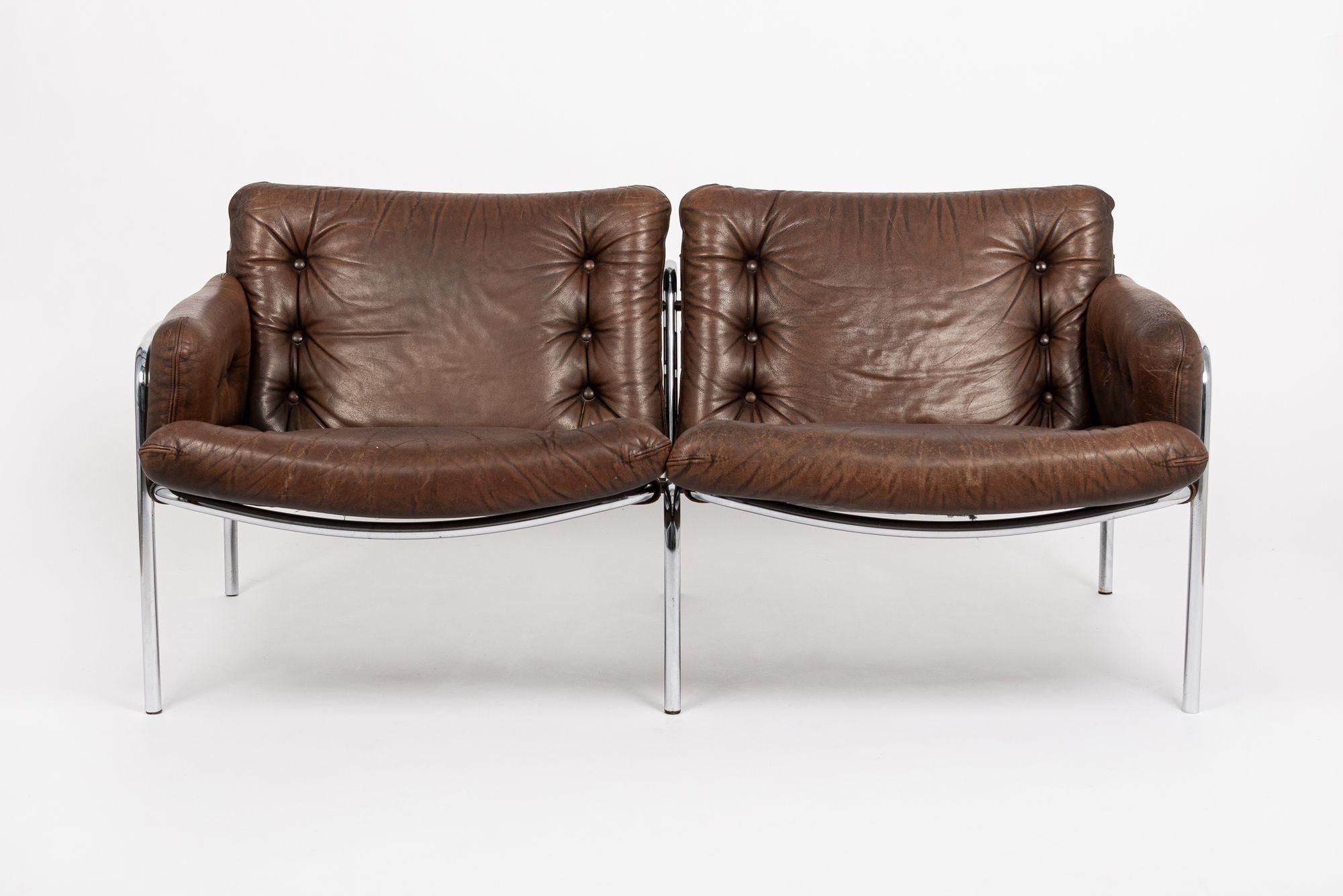 This incredible vintage mid century modern loveseat couch is circa 1970. The unique two-seat loveseat sofa is sturdy and well-built with incredible vintage style and features button-tufted seat and backrest cushions in original distressed brown
