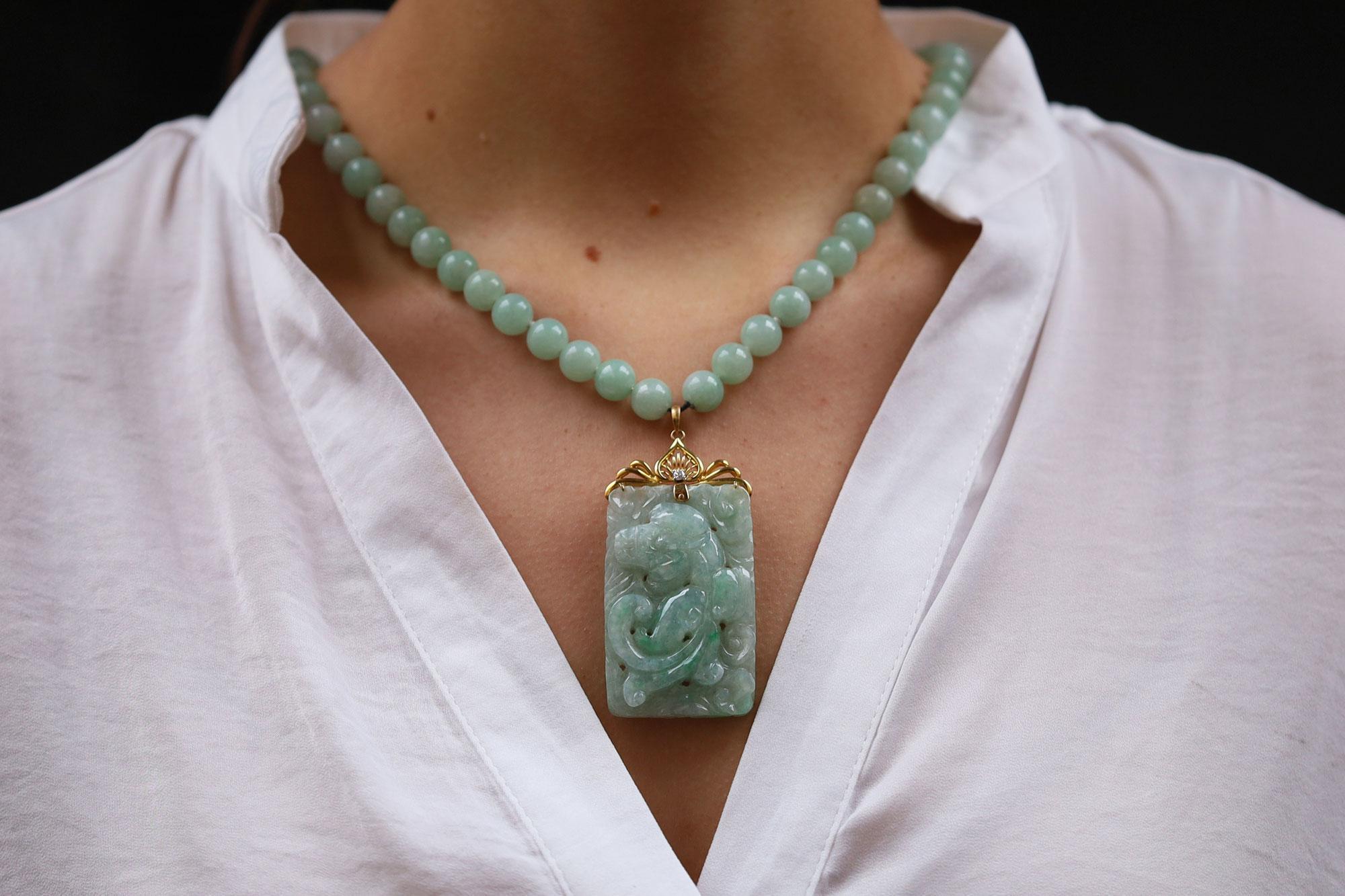 With a crisp, refreshing apple green color, this vintage natural jade dragon necklace is an heirloom to be treasured. The 60 jadeite beads terminate with a finely carved plaque pendant topped with a 14 karat yellow gold and diamond lotus. This