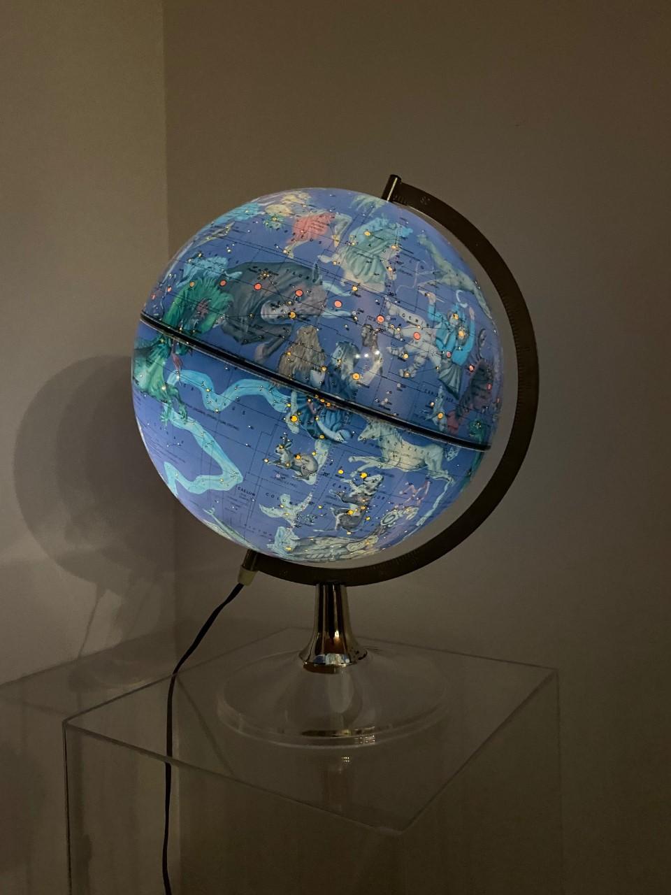 Beautiful illuminated constellation globe. This piece is magical, glamorous and chic. The lucite base holds the beautiful blue globe that when illuminated reveals the constellations in their most magical and artistic form. Cartography for this piece