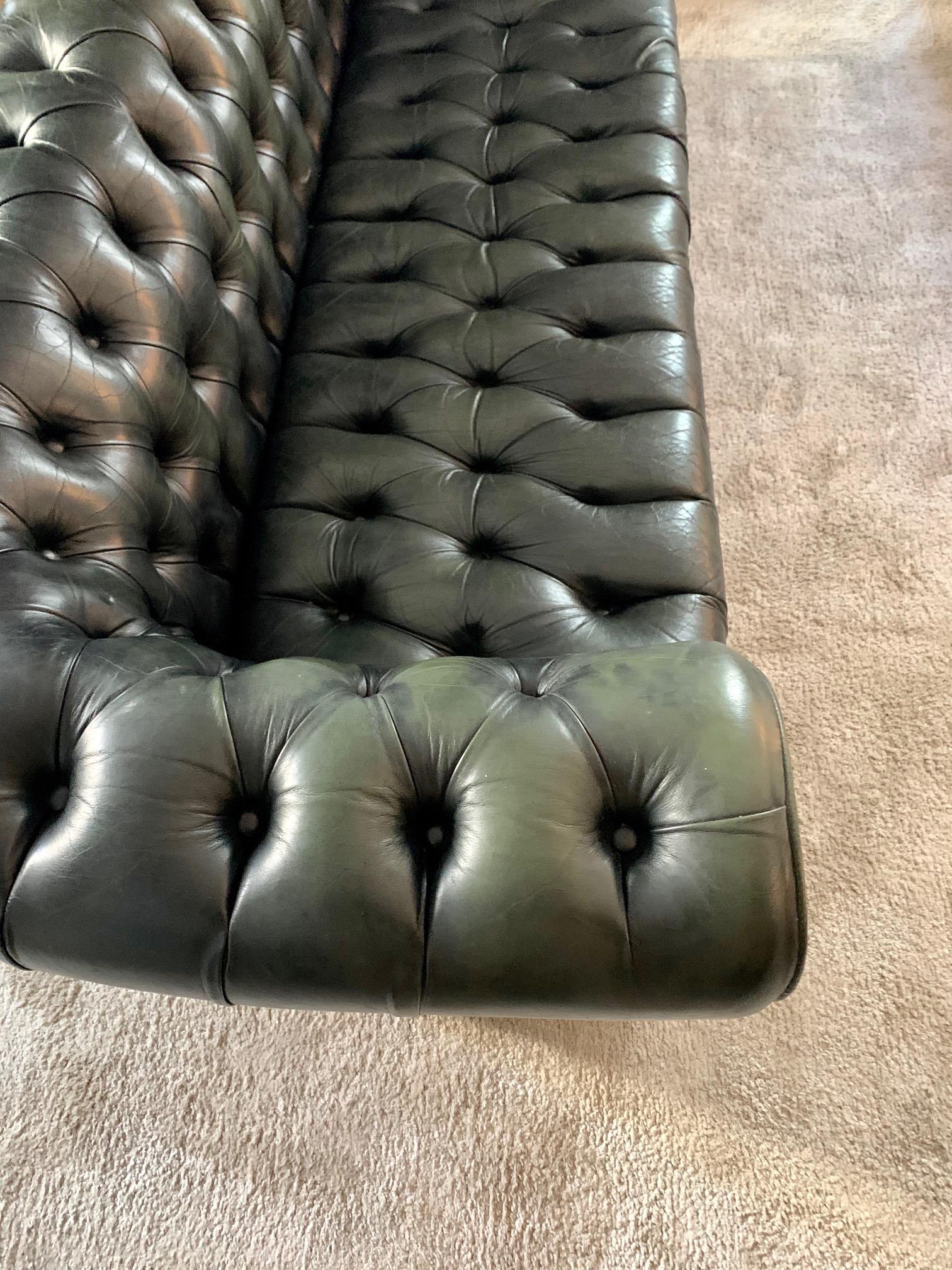 Early to mid-20th century vintage leather Chesterfield sofa, elegant models with button down seating, in dark green leather and round wooden feets.
  
