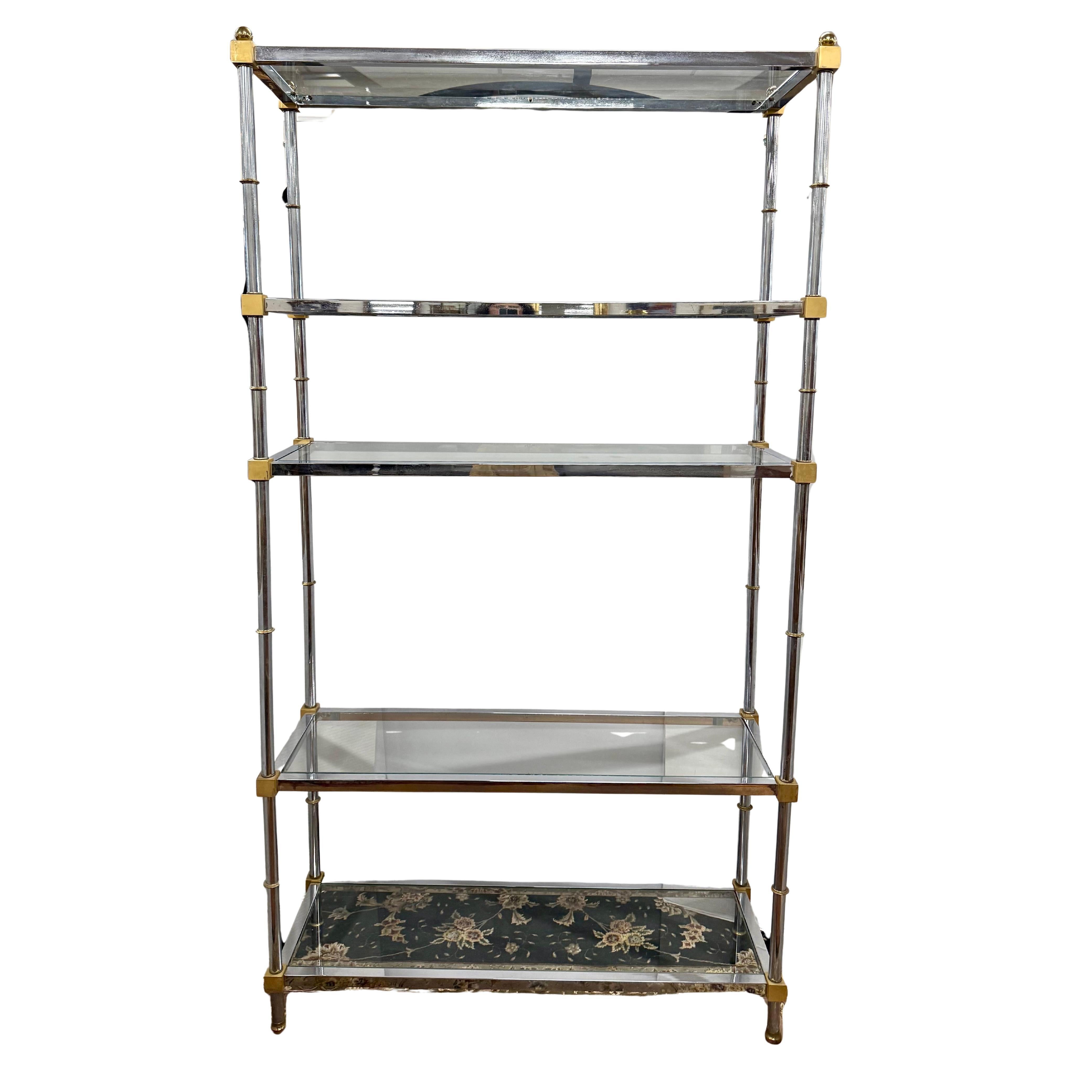 Diese verchromte und messingfarbene Etagere aus der Mitte des Jahrhunderts mit einem eleganten verchromten Stahlrahmen und glänzenden Ecken und Endstücken aus massivem Messing hat einen luxuriösen zweifarbigen Look.
Fünf Ablagen aus Klarglas bieten