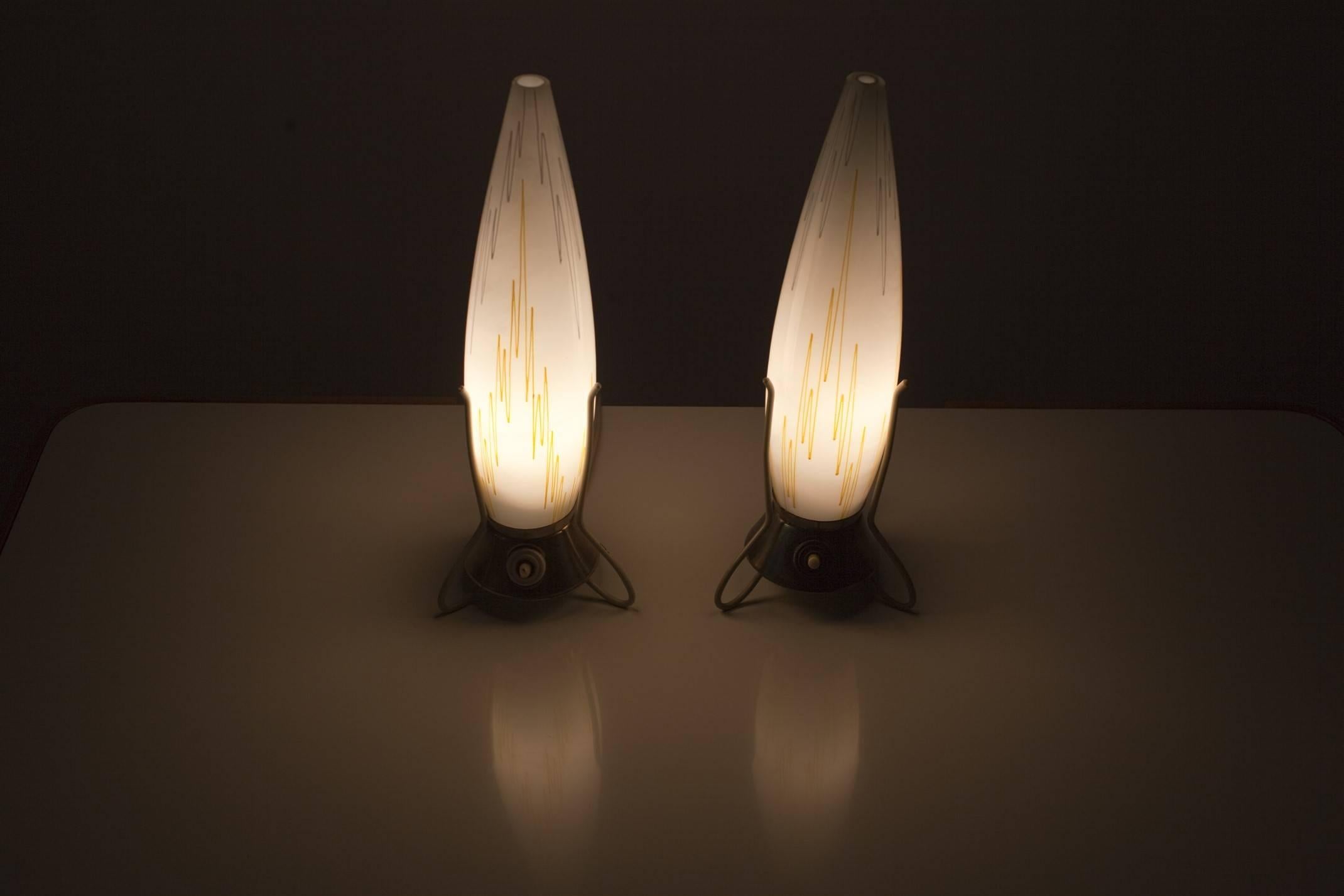 Cette paire de lampes de table du milieu du siècle a été fabriquée dans les années 1960. Les lampes sont posées sur une base tripode et leurs abat-jour ont la forme d'une fusée.
