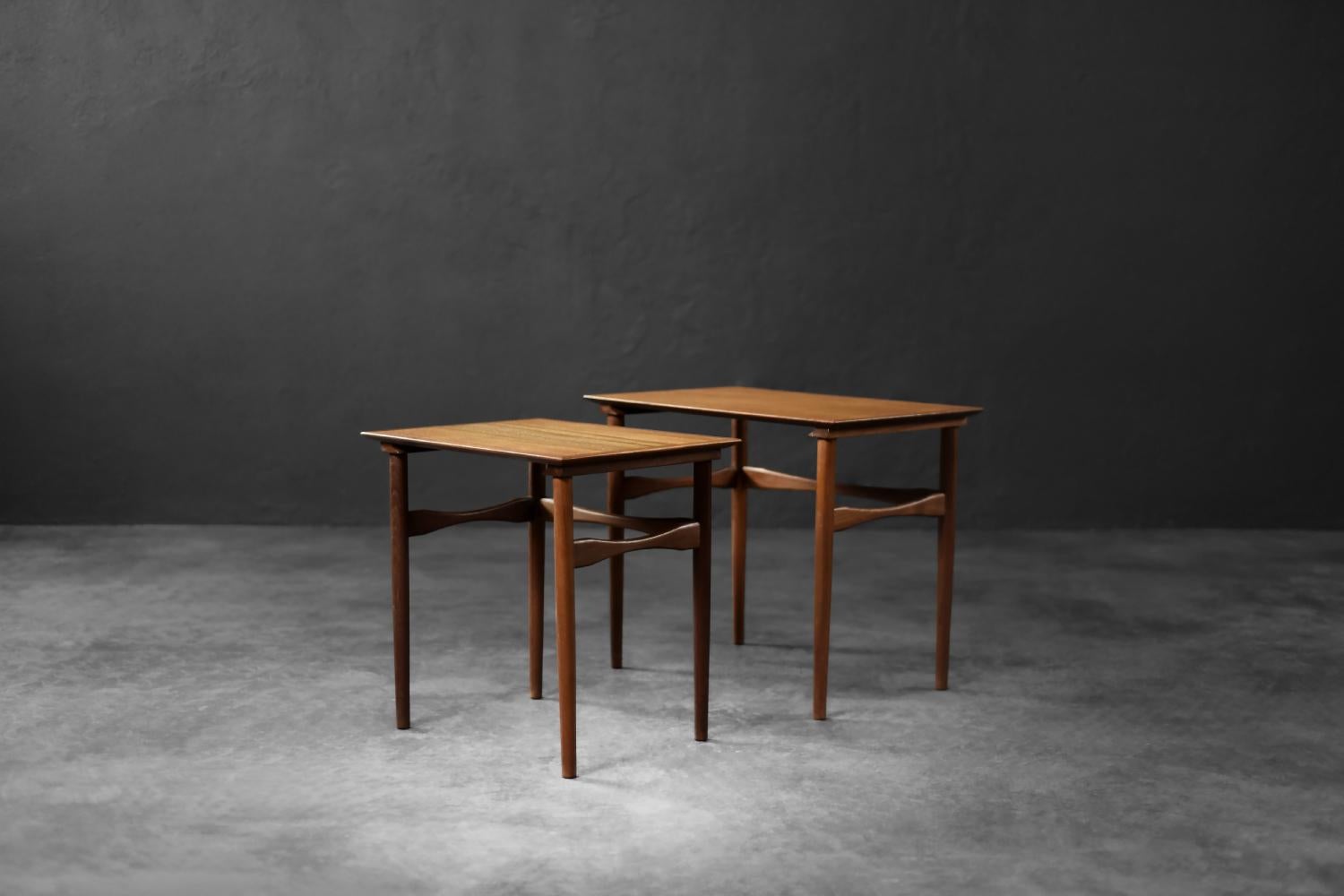 Questo set di due tavolini Nesting è stato prodotto in Danimarca negli anni '60. I tavoli rettangolari sono realizzati in teak marrone scuro con venature profonde e distinte. Colpiscono per la loro forma minimalista e la precisione artigianale