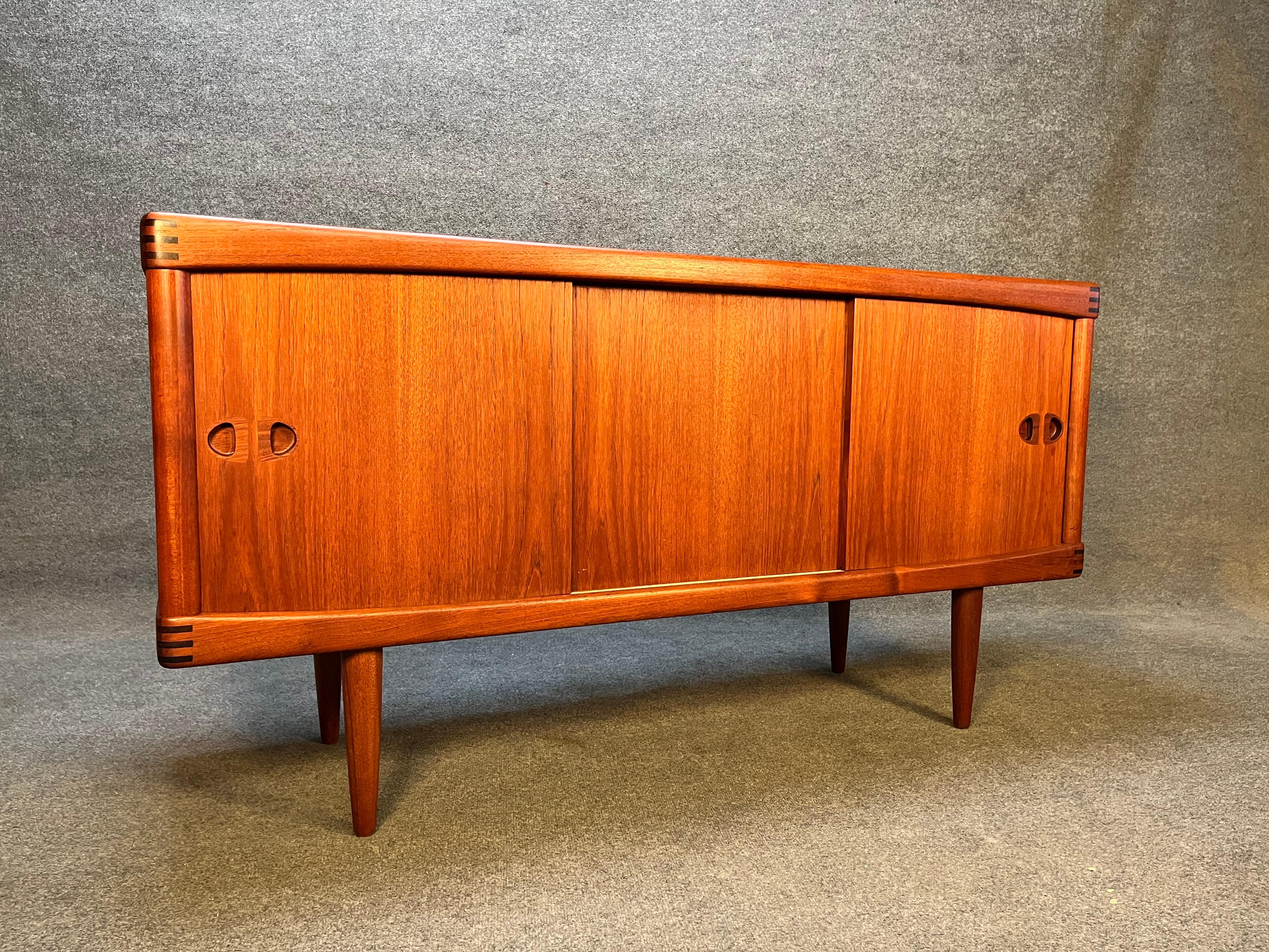 Here is a rare and beautiful credenza designed by H.W. Klein for Bramin Møbler in Denmark circa 1960’s. Impeccably crafted in teak wood, this compact credenza offers two sliding doors on each side with shelved compartments within. Each door features