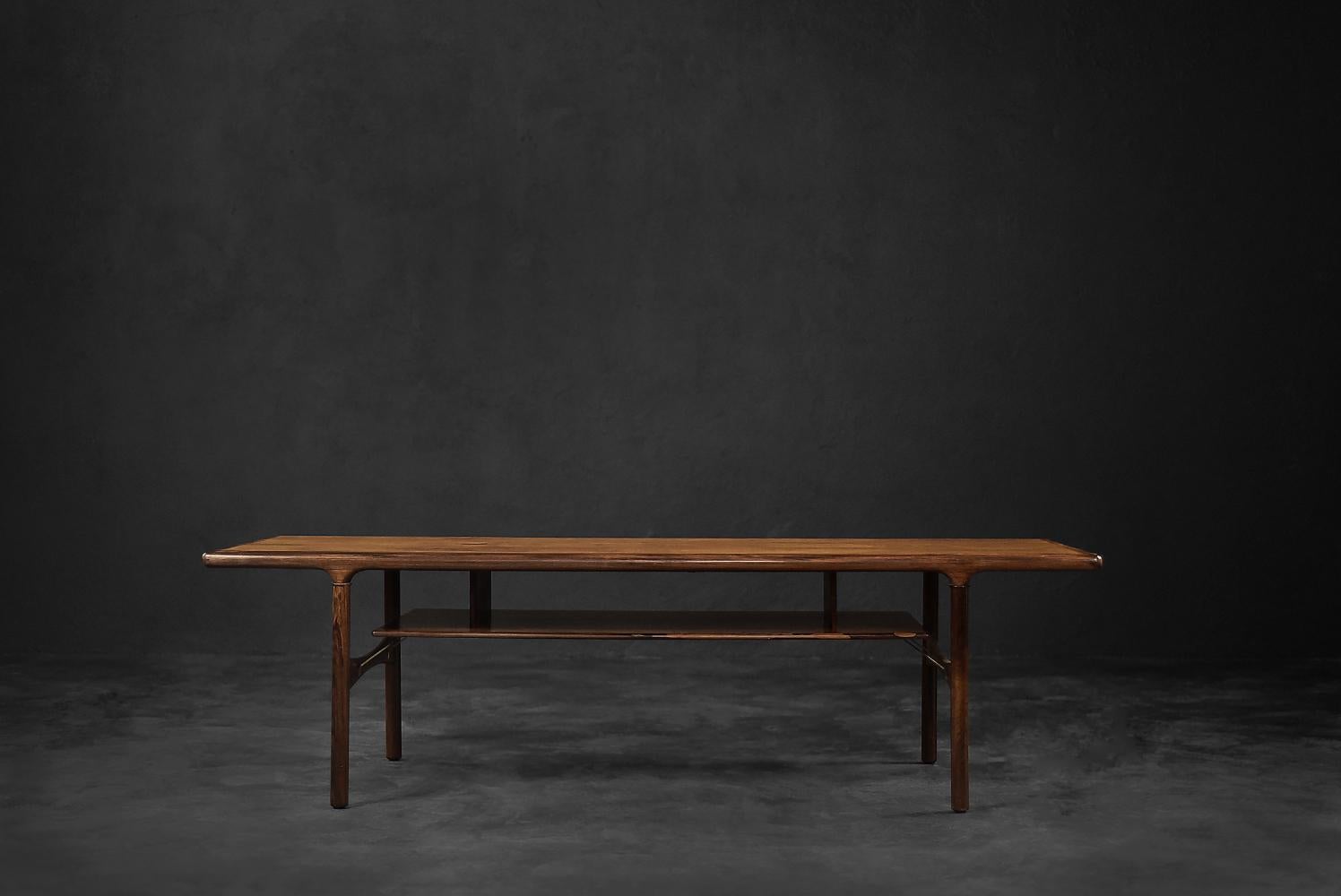 This elegant coffee table was made in Denmark during the 1960s. It is made of high-quality, precious rosewood in a dark shade of brown. This noble kind of wood has an exceptionally dynamic, clear and consistent graining. The table has a shelf