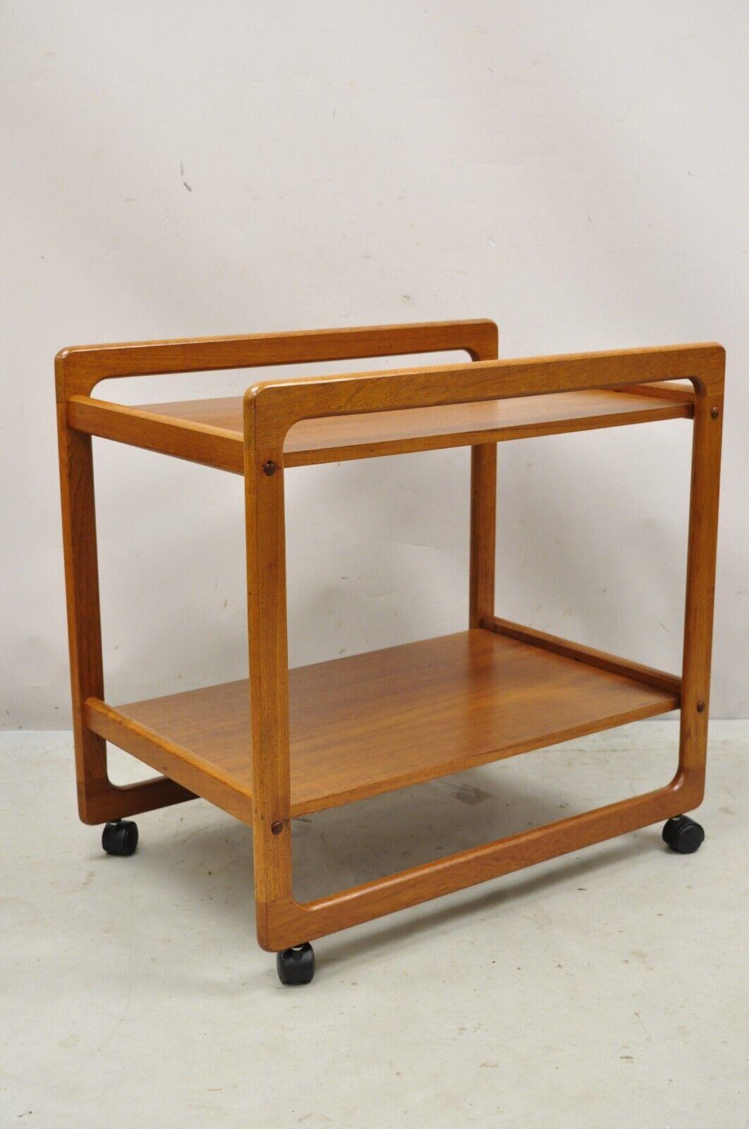 Vintage midcentury Danish Modern teak 2 tier rolling bar cart server table. Item features rolling casters, 2 tiers, beautiful wood grain, very nice vintage item, clean modernist lines, circa Late 20th Century. Measurements: 27.5