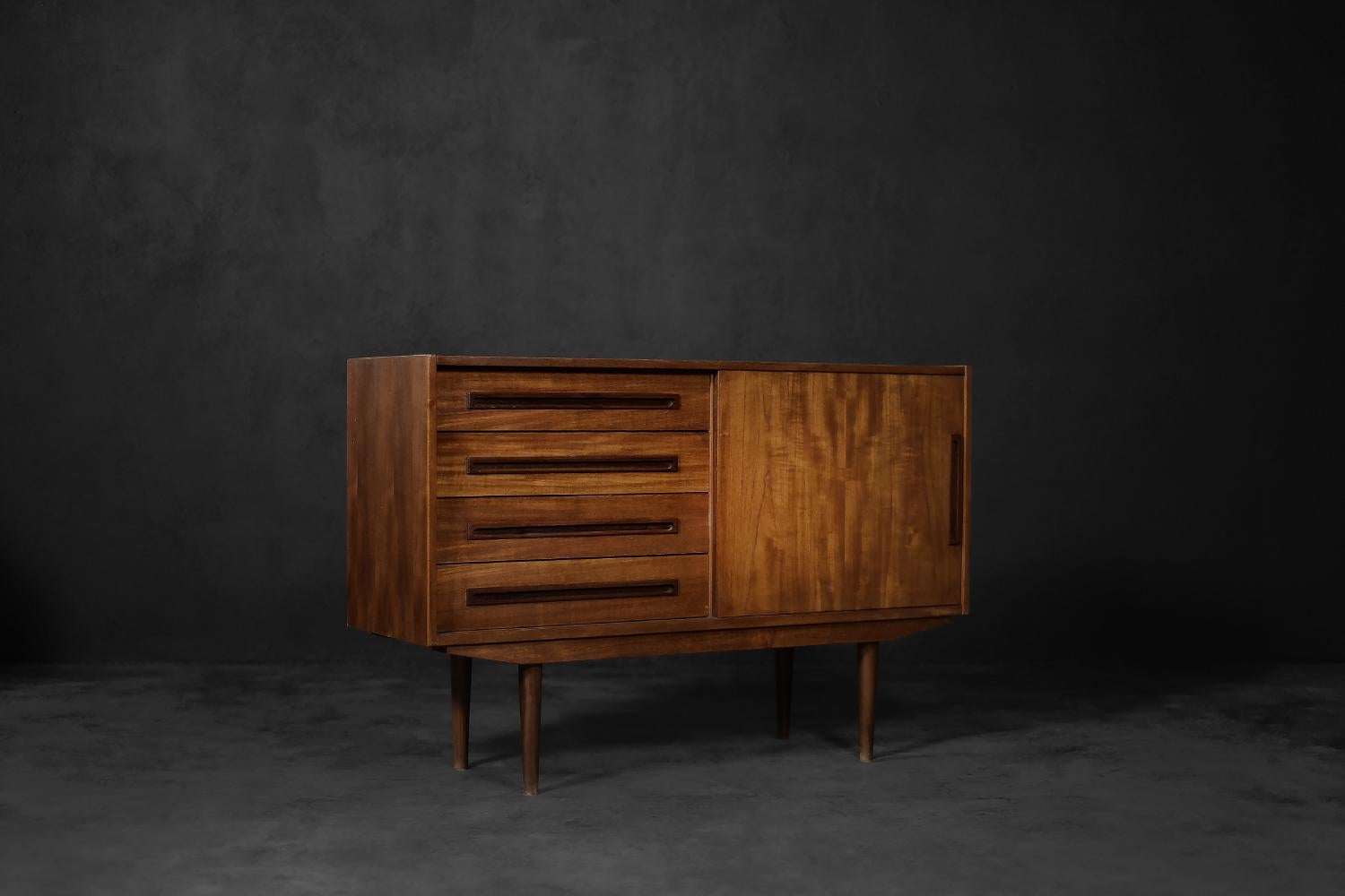 This classic chest of drawers was made in Denmark during the 1960s. It is finished with teak wood with regular grain and a warm, brown color. The chest of drawers has four wide drawers. Long, wooden handles are a perfect complement to them. The