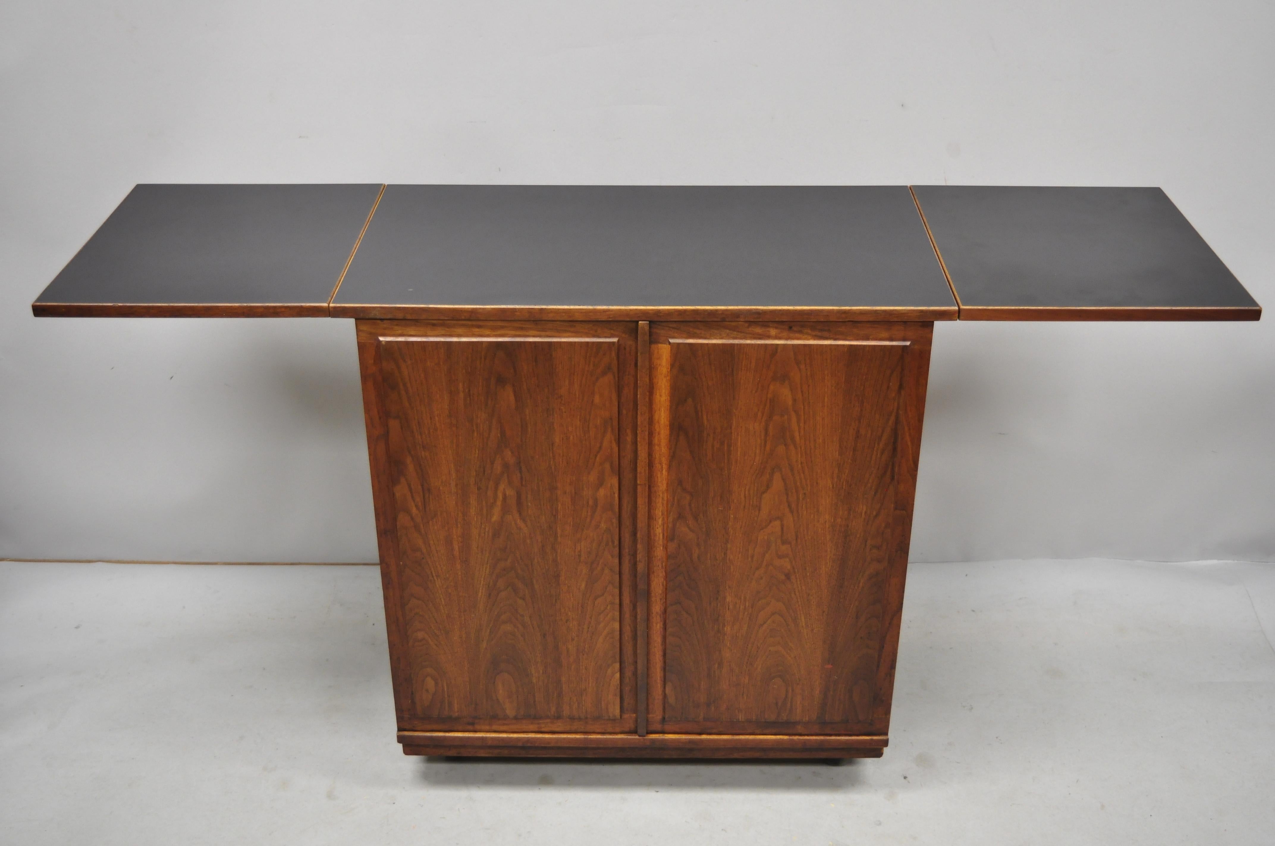Vintage midcentury Danish modern teak drop-leaf rolling bar cart cabinet. Listing includes rolling casters, beautiful wood grain, laminate top, finished back, 2 swing doors, 1 dovetailed drawer, 1 wooden shelf, circa mid-20th century. Measurements: