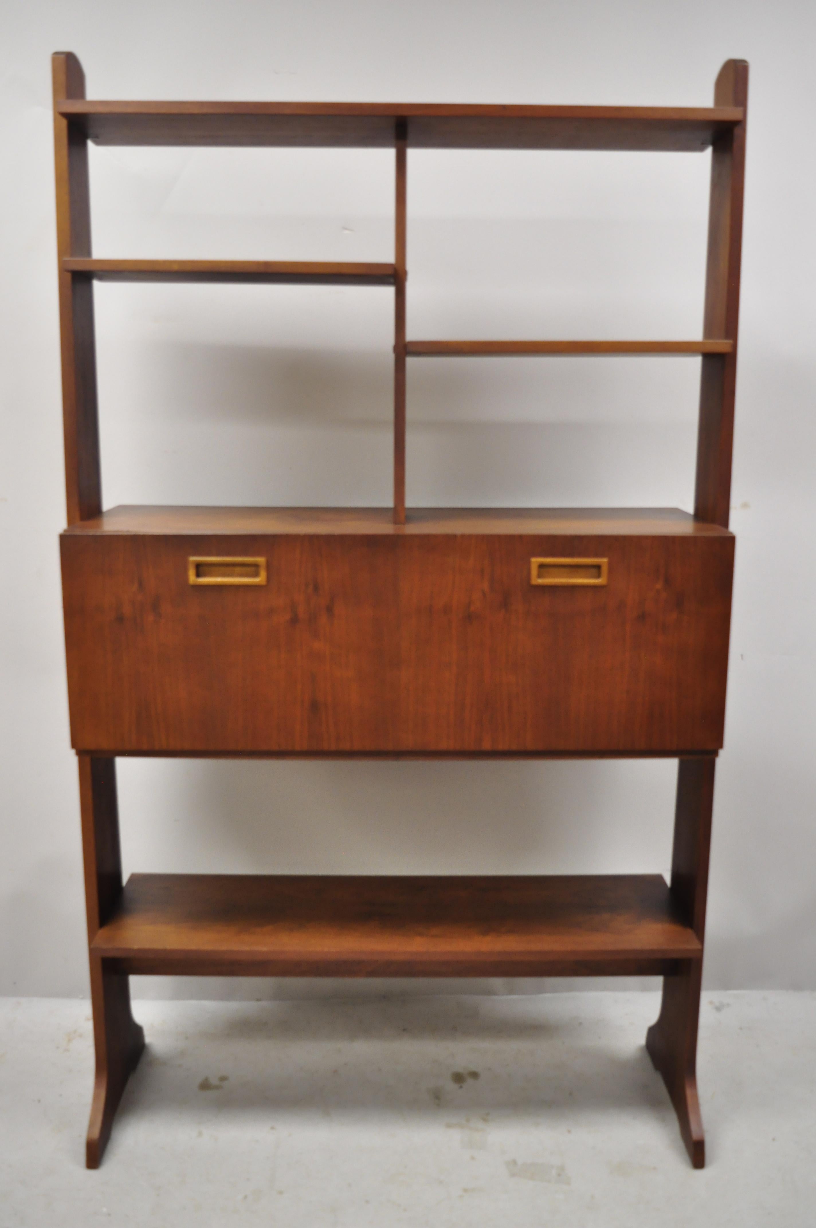 Vintage midcentury Danish modern teak wall unit bookcase display cabinet. Item features 1 fall front door, desk fitted interior, sculpted wood pulls, beautiful wood grain, finished back, very nice vintage item, sleek sculptural form,
circa mid-20th