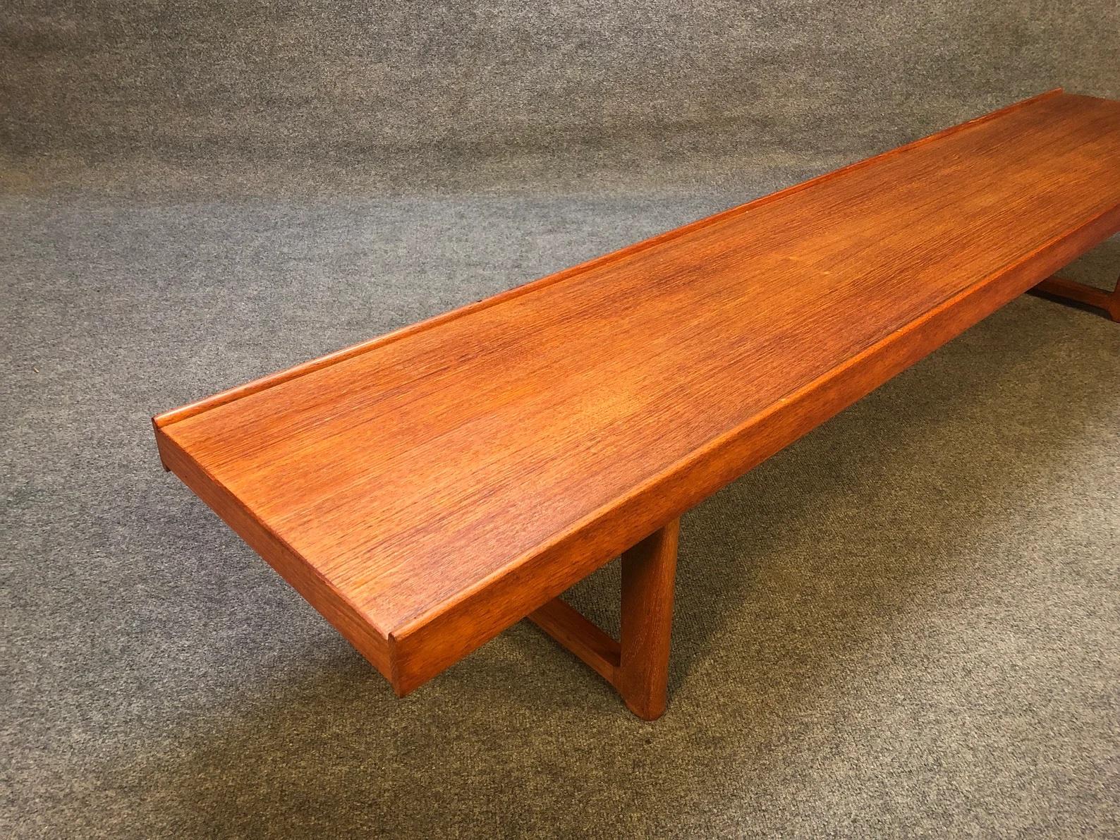 A Scandinavian Modern bench in a simple plank form in teak with two raised edges then resting on legs that join at the floor creating U-shaped pedestal bases. By Torbjörn Afdal for Mellemstrands Trevareindustri and distributed by Bruksbo Møbler.