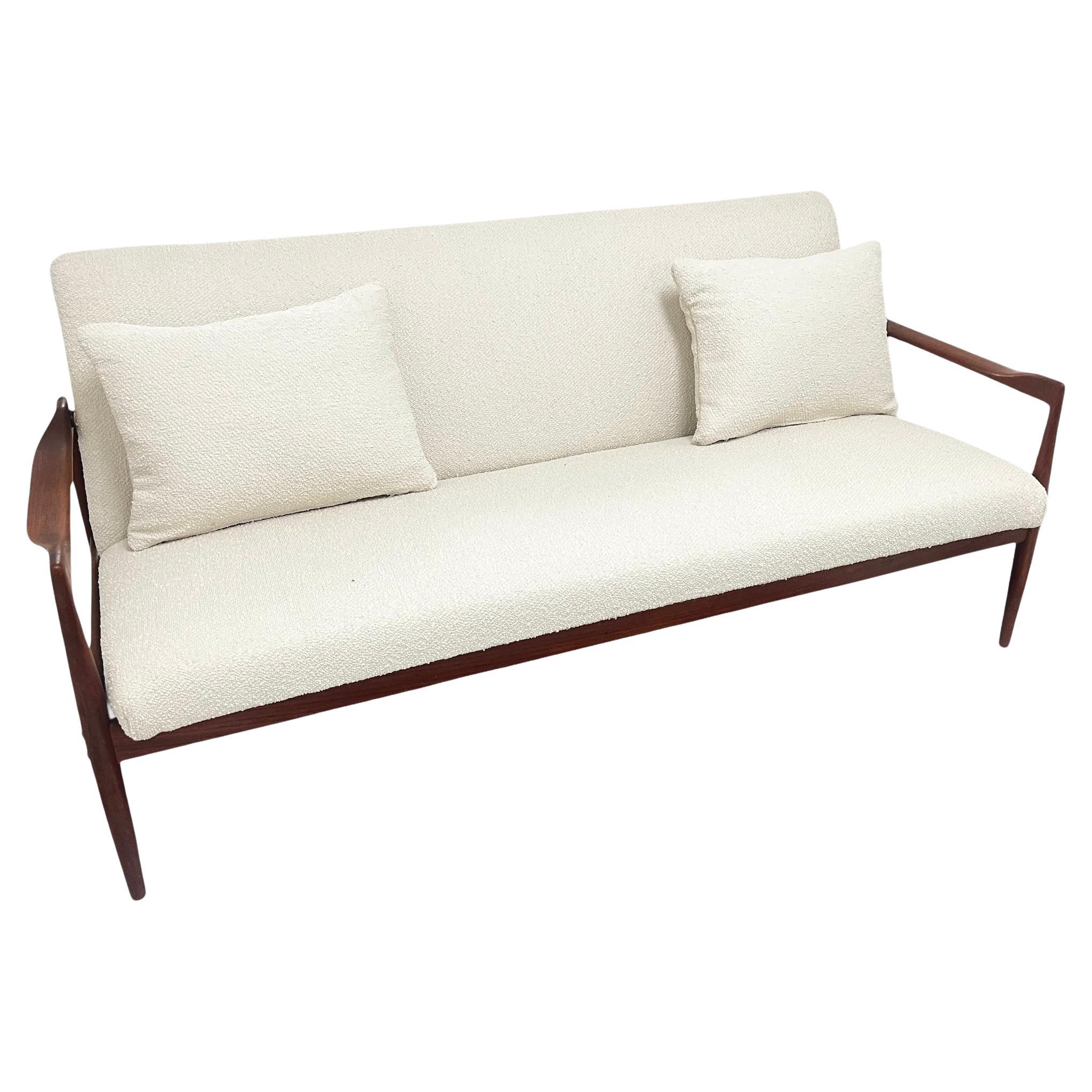 Vintage Mid-Century Danish Teakwood Sofa. Maintains the Danish Furniture control sticker. No Makers Marks. Overall great vintage condition with age appropriate wear. Sofa has been reupholstered with an off white boucle fabric.  Two Boucle throw