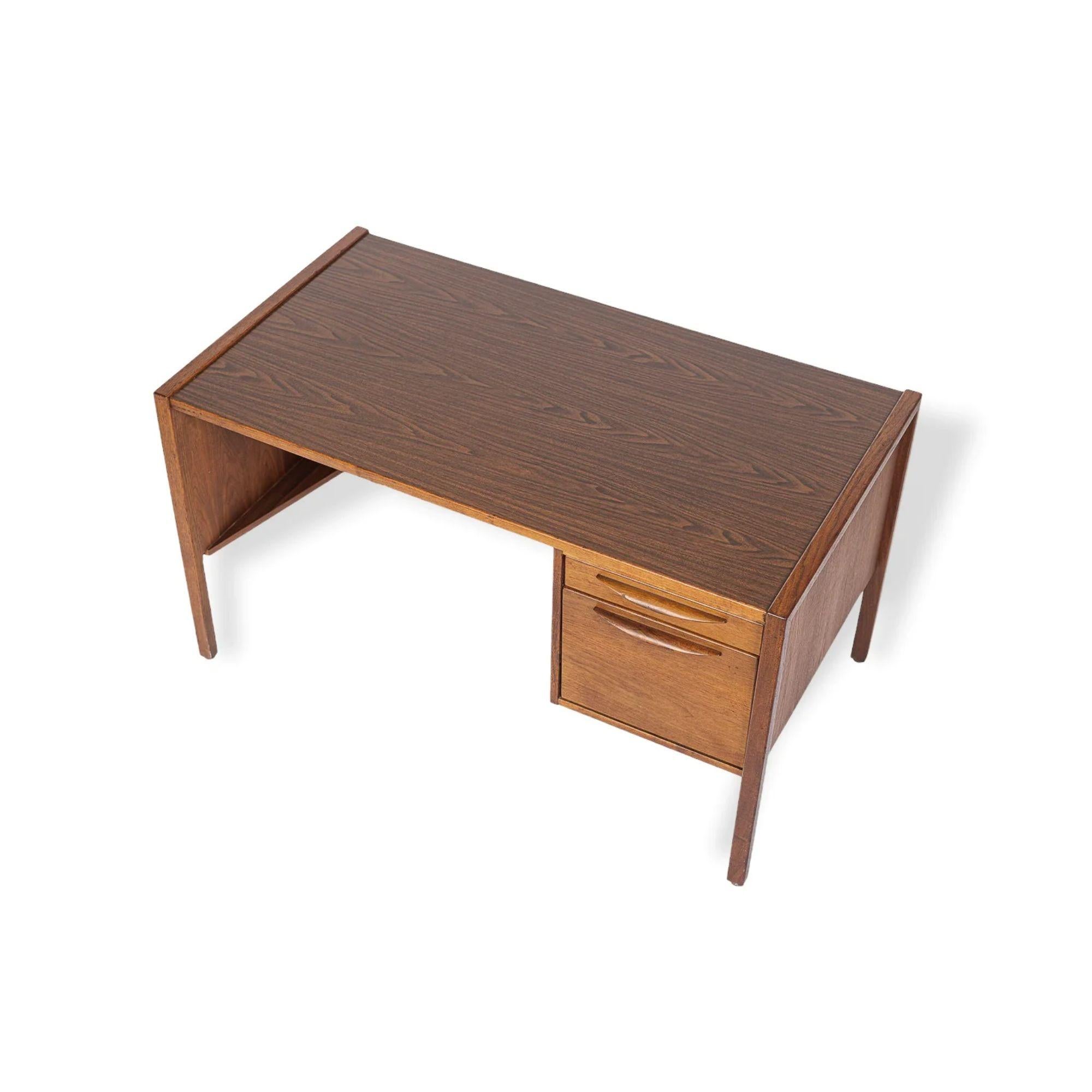 This vintage Mid-Century Modern desk by Jens Risom circa 1960 has a Classic Danish modern design with clean, Minimalist, geometric lines. The desk is solid, heavy and well-crafted and features a solid walnut wood frame with laminate top and back.