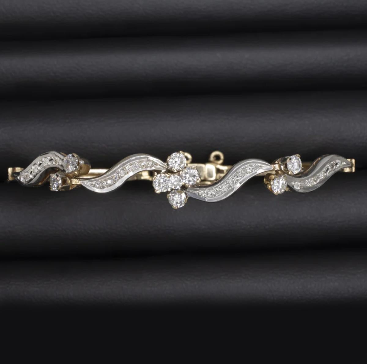 This elegant mid-century estate bracelet is crafted in a striking combination of 14K yellow and white gold, showcasing a sculptural swirl design set with vibrant clusters of diamonds. The piece features a total of 1.00 carat of natural round and