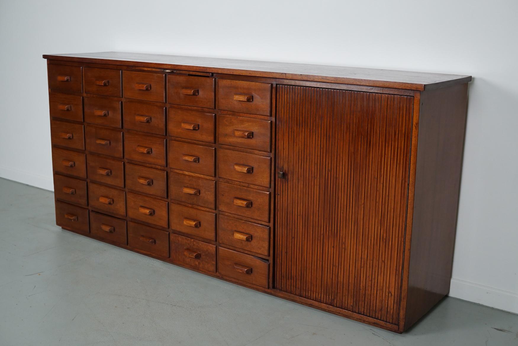 This cabinet was produced during the 1950/60s in the Netherlands. It features drawers in mahogany  and a large door with a shelve behind it. It was originally used in pharmacy in Amsterdam. The interior dimensions of the drawers are: D x W x H 34 x