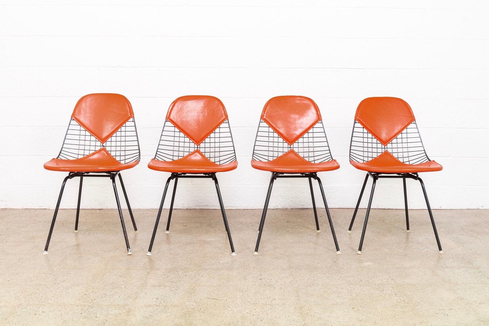 These original vintage Charles and Ray Eames for Herman Miller DKX-2 red bikini chairs designed in the late 1950s are early production circa 1960. The iconic modernist design features welded black steel wire tubular frames with H-bases and original