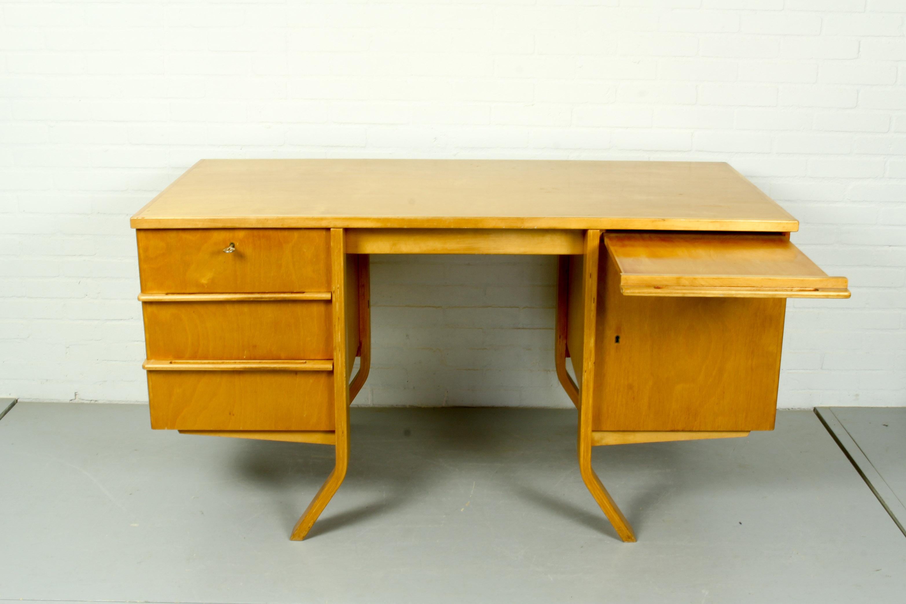 Beautiful writing desk designed by Cees Braakman for Pastoe in the early 1950s. This EB04 desk is part of the 'Birch Series'. It has 3 drawers on the left and on the right a door with 2 shelves behind and an additional working leaf above. The door