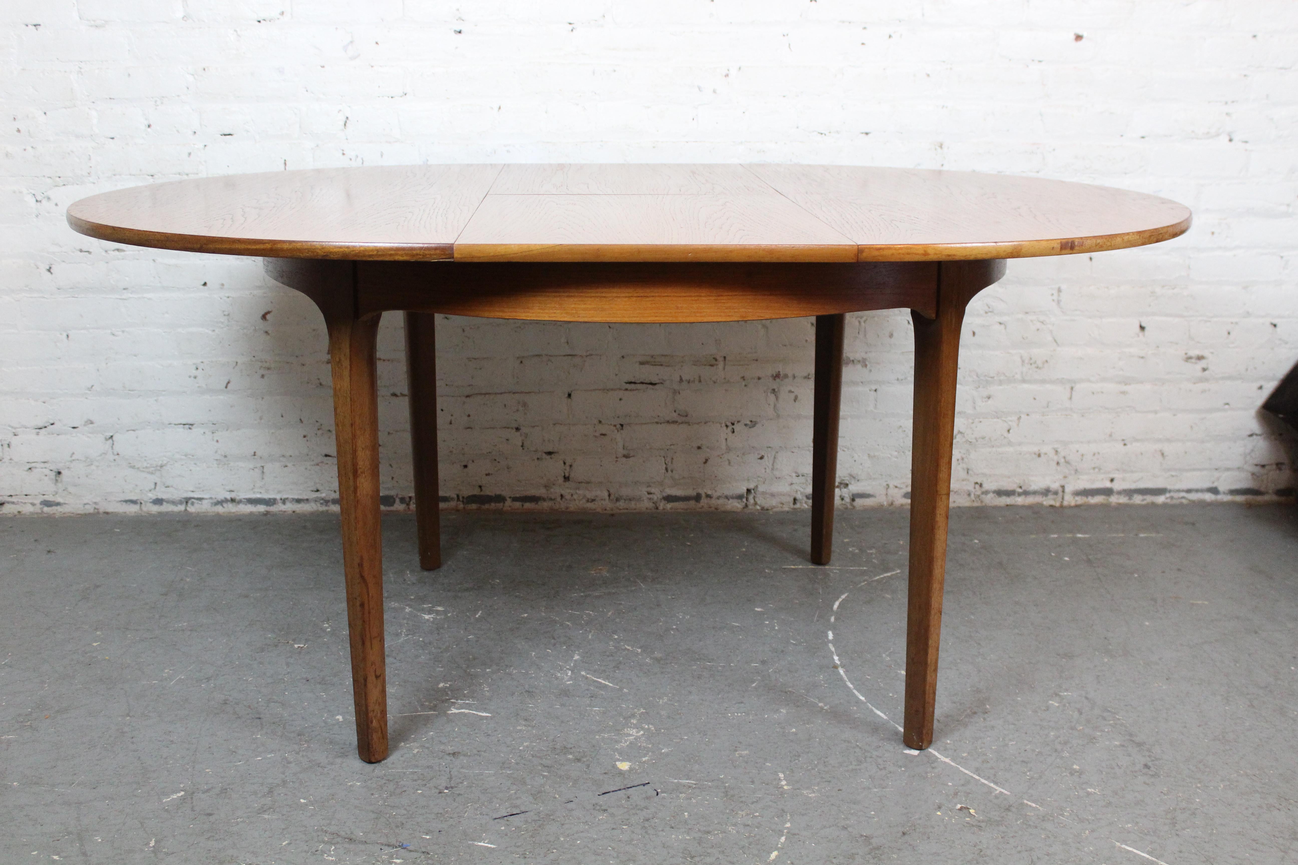 Abraza la sutil genialidad del diseño de muebles modernos de mediados de siglo con esta fascinante mesa mariposa expansible, construida por los talentosos artesanos de la estimada Nathan Furniture Company de Londres, Inglaterra. Fabricada en madera
