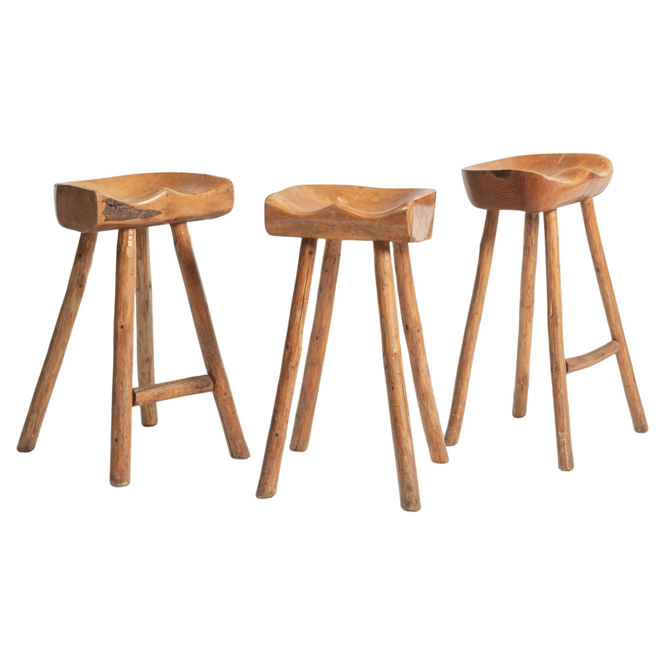 These Vintage High Stools are hand crafted of hardwood, with a saddle seat and tapered legs. They are rustic yet quite comfortable. The seat is hand-sculpted to follow the natural contours of the human form and sanded to reveal the beautiful grain