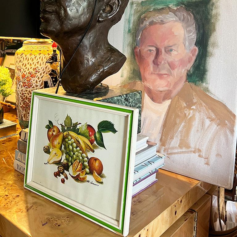Ein farbenfrohes Stillleben mit Früchten in einem leuchtend grünen und weißen Rahmen. Dieses Stück würde sich gut auf einem Regal in einer Küche auf einer Arbeitsplatte machen, die an einer Aufkantung anliegt. Oder vielleicht sogar an der Wand in