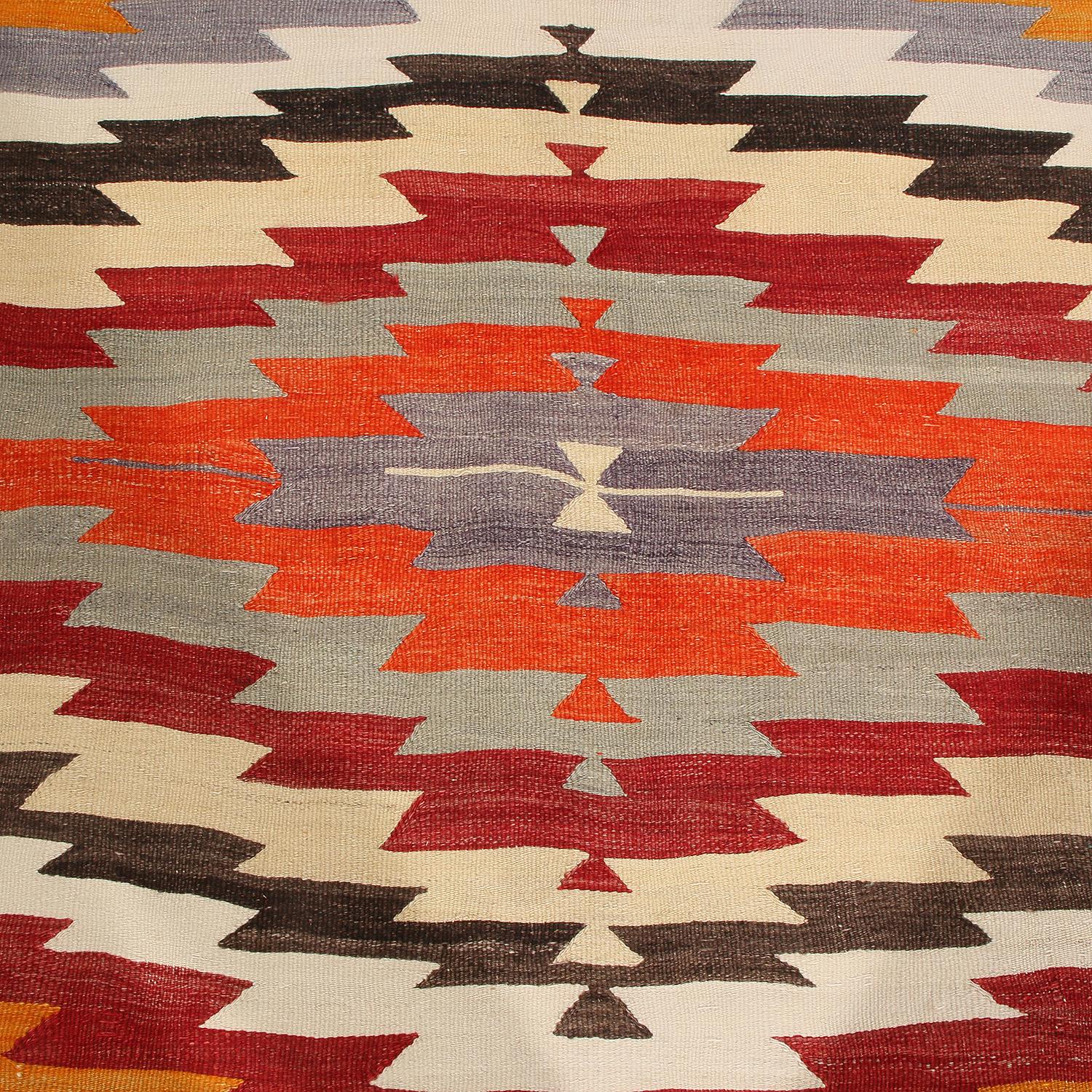 Dieser geometrische Vintage-Kilim-Teppich wurde zwischen 1940 und 1950 aus hochwertiger Wolle in der Türkei von Hand flach gewebt und besticht durch eine Reihe einzigartiger Farben, die das schlichte, aber exzentrische Felddesign durch eine subtile