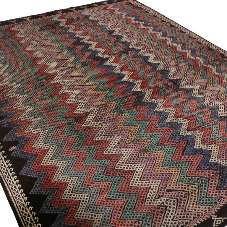 handwoven in Turkey originating between 1950-1960, this vintage wool Kilim rug enjoys a unique versatility in design appeal through the skillful play of both vibrant and muted hues in the lively chevron geometry. The phenomenal sense of movement