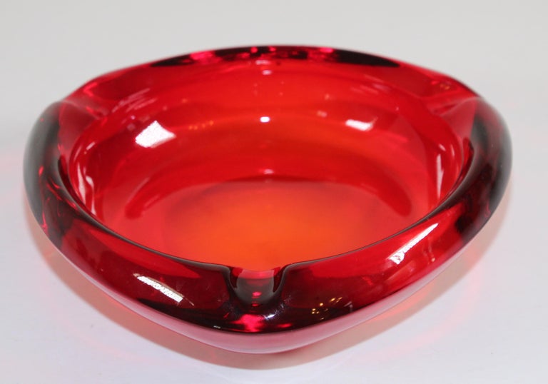 Vintage modernist mid-century glass ashtray ruby red triangular.
Mid-century glass ashtray circa 1960's - 1970's USA. 
Large and stunningly beautiful art glass ashtray by Viking in their beautiful ruby red color. 
Back when people still smoked