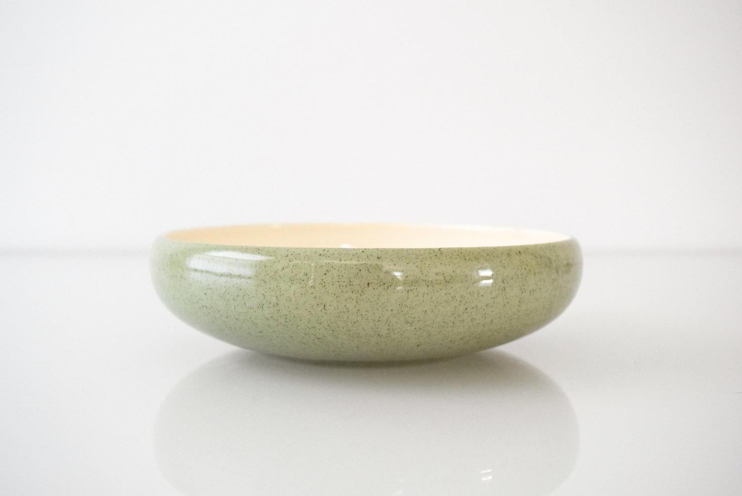 • Vintage Mid-Century Modern small ceramic bowl.
• Simple modernist design with a pretty shape, shallow profile and gentle curved edge.
• Pale sage exterior with tiny black speckles and bone interior.

Dimensions
Diameter: 7 1/2
