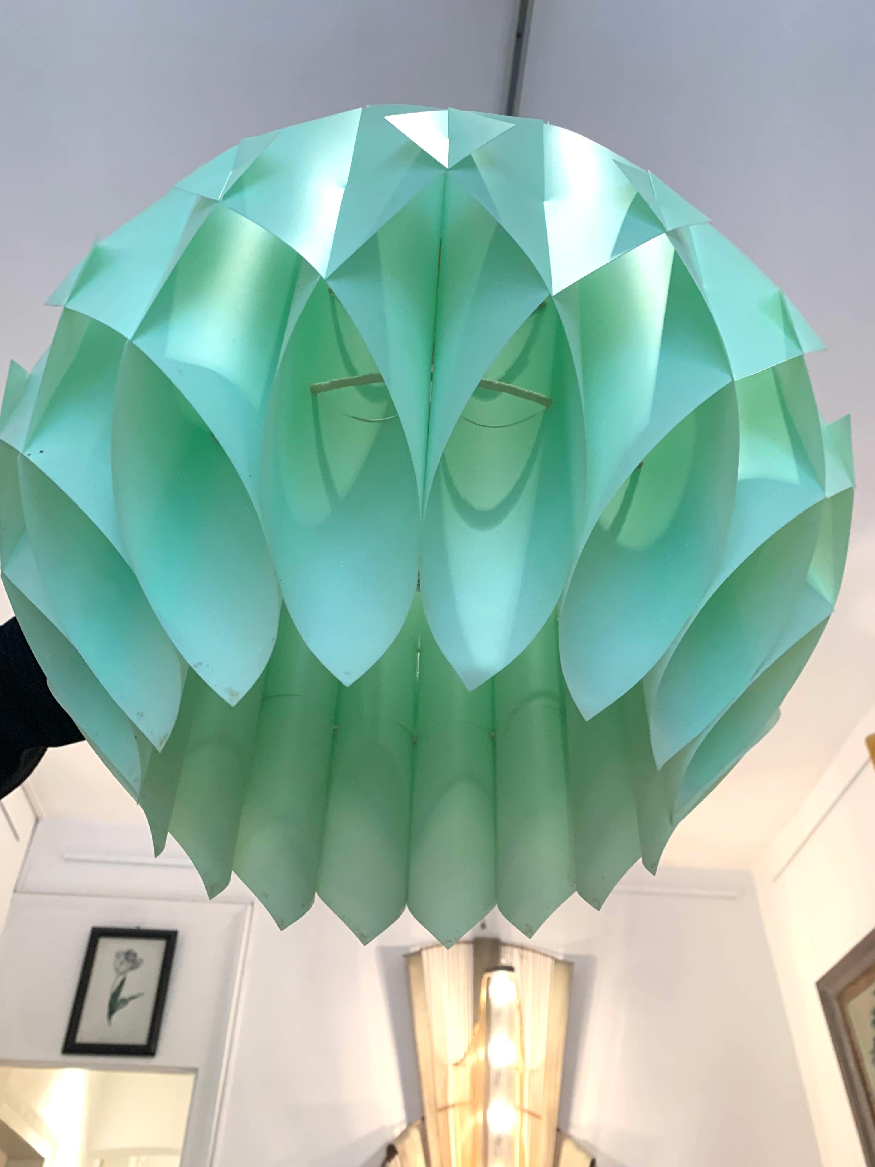 The pendant lampshade is designed as a ball put together out of different abstract elements. Squares and cylinders with tapered edges made out of light green thick flexible plastic sheet have been interlocked to create this exciting structure. The