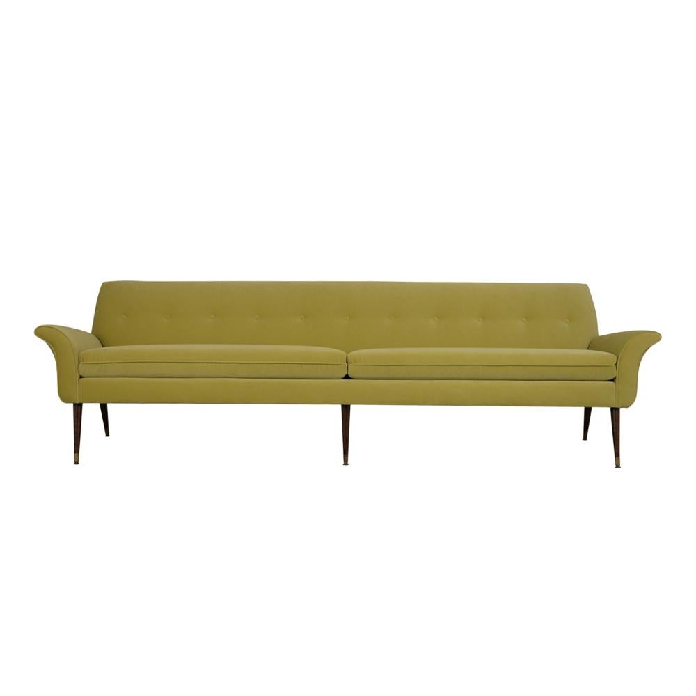 An extraordinary Danish mid-century sofa crafted out of solid wood that has been professionally restored and has been newly upholstered in a delightful lime green color velvet fabric. The sofa features tufted bottoms on the back scrolled design arms