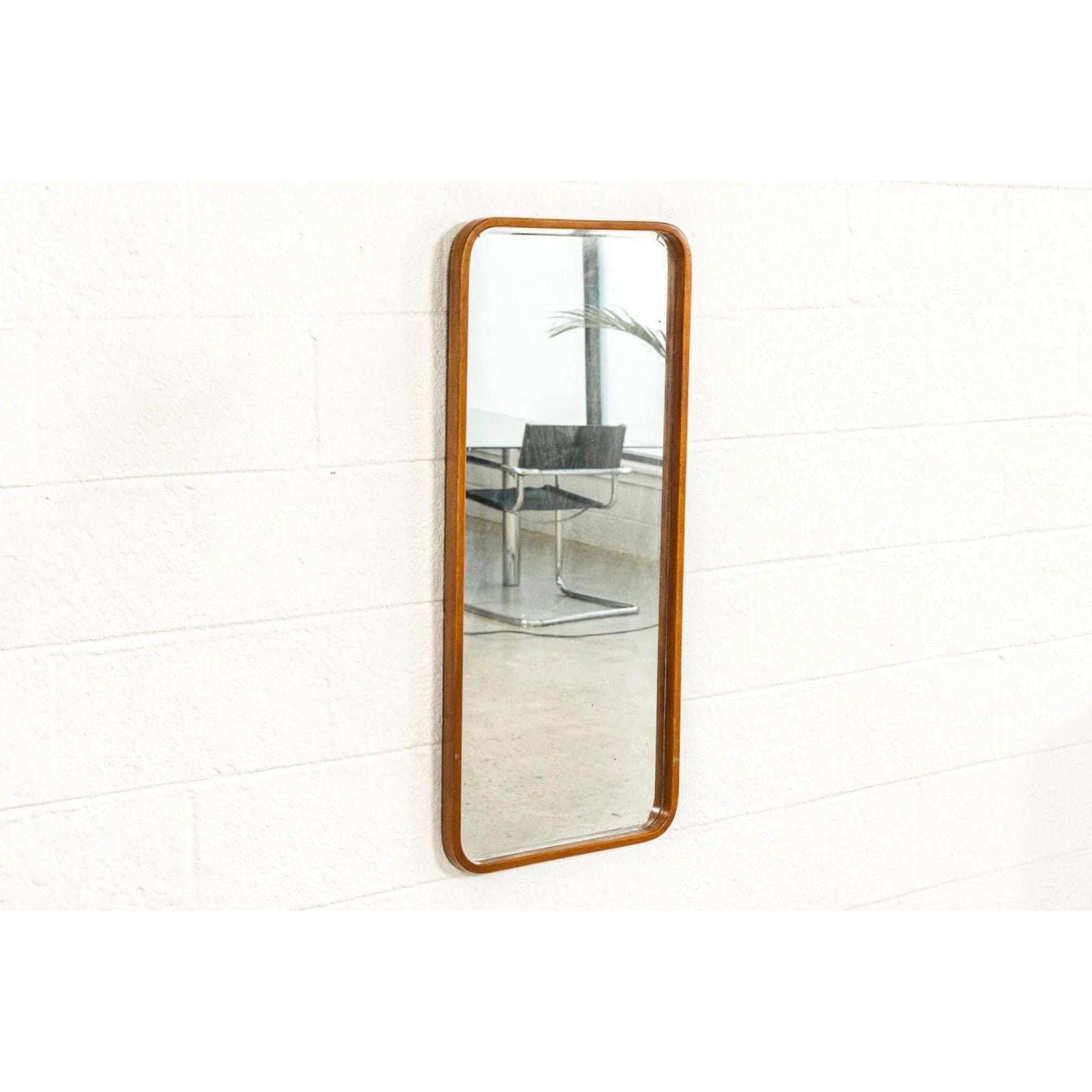 Vintage Mid Century Teak Wood Hanging Wall Mirror, 1960s

This vintage mid century modern wall mirror is circa 1960. It features a clean, minimalist design with a beveled mirror and box frame with rounded bentwood corners well-crafted from solid