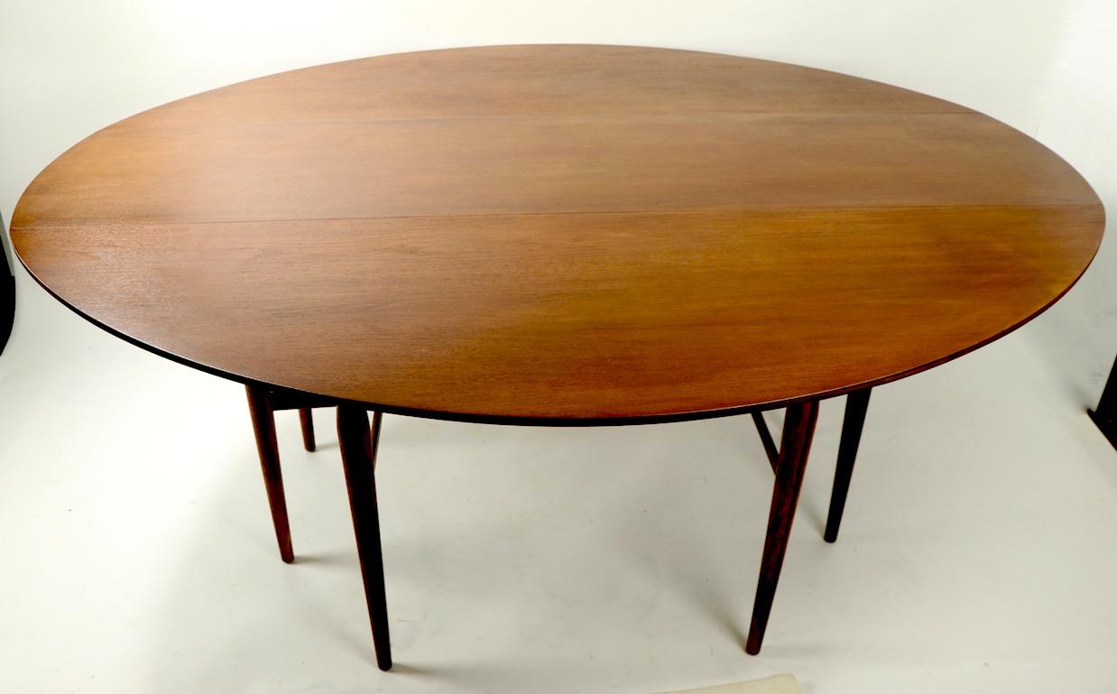 Stylish and versitile design, classic long drop-leaf table, by Henredon. This example is in very clean ready to use condition, the top has been newly professionally refinished. Dimensions with leaves down 19 D x 60 D with leaves in up position each