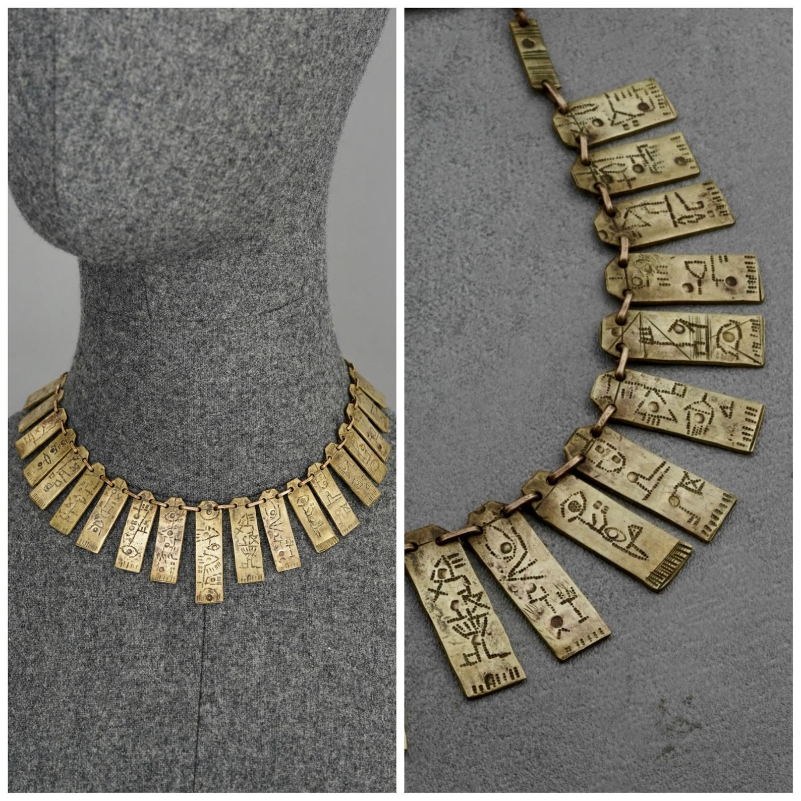Vintage Mid Century Inca Symbol Plates Choker Necklace

Measurements:
Symbol: 1.57 inches (4 cm)
Wearable Length: 14.96 inches (38 cm)

Features:
- Mid century choker necklace with Inca symbols engraved on plate charms.
- Bronze tone.
- Hook
