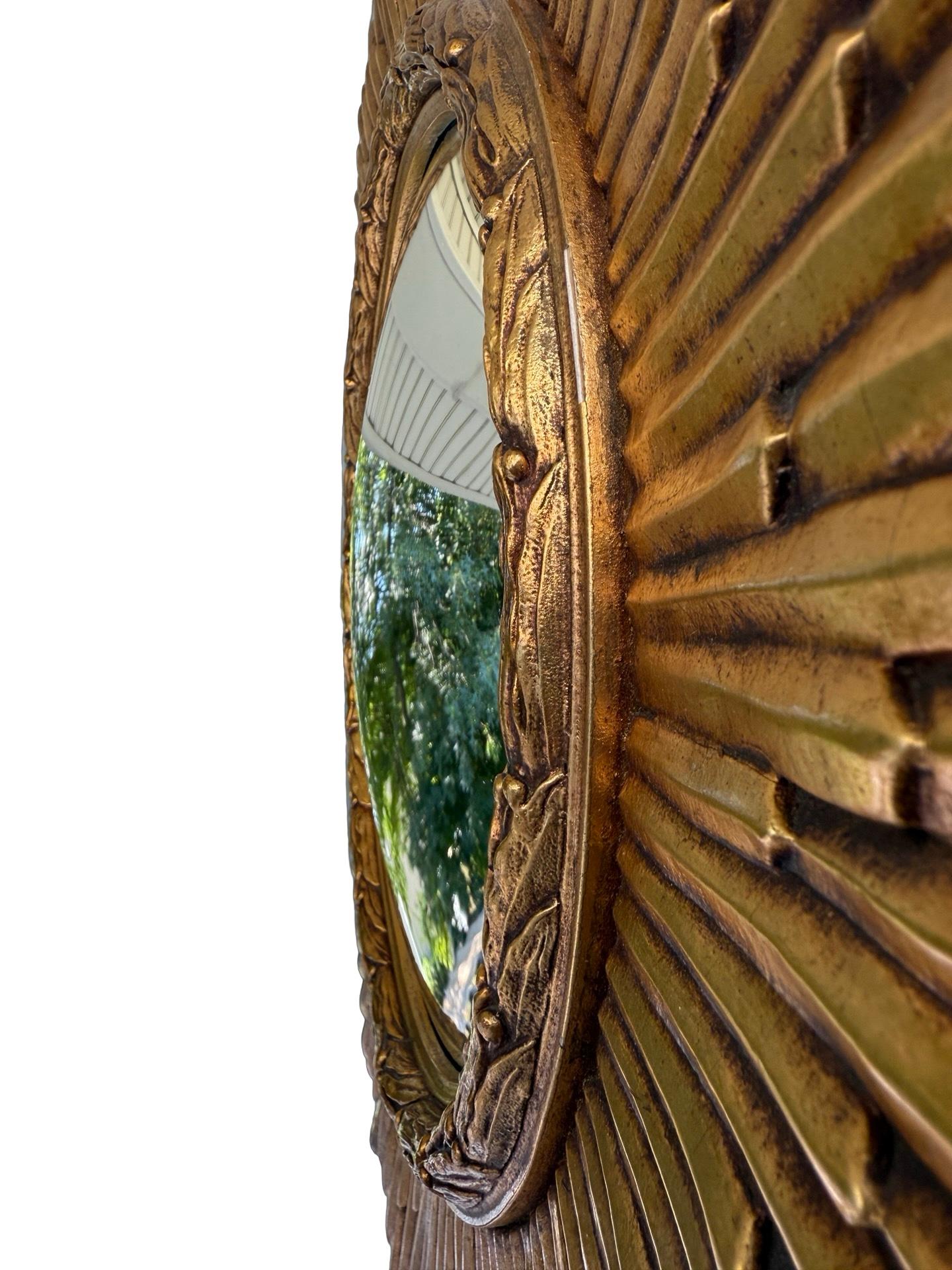 Dieser auffällige italienische Sonnenschliffspiegel im Vintage-Stil hat einen kühn geschnitzten, radialen Rahmen aus vergoldetem Holz, in dessen Mitte sich eine konvexe Spiegelplatte befindet, die die dekorative Sprache der klassischen