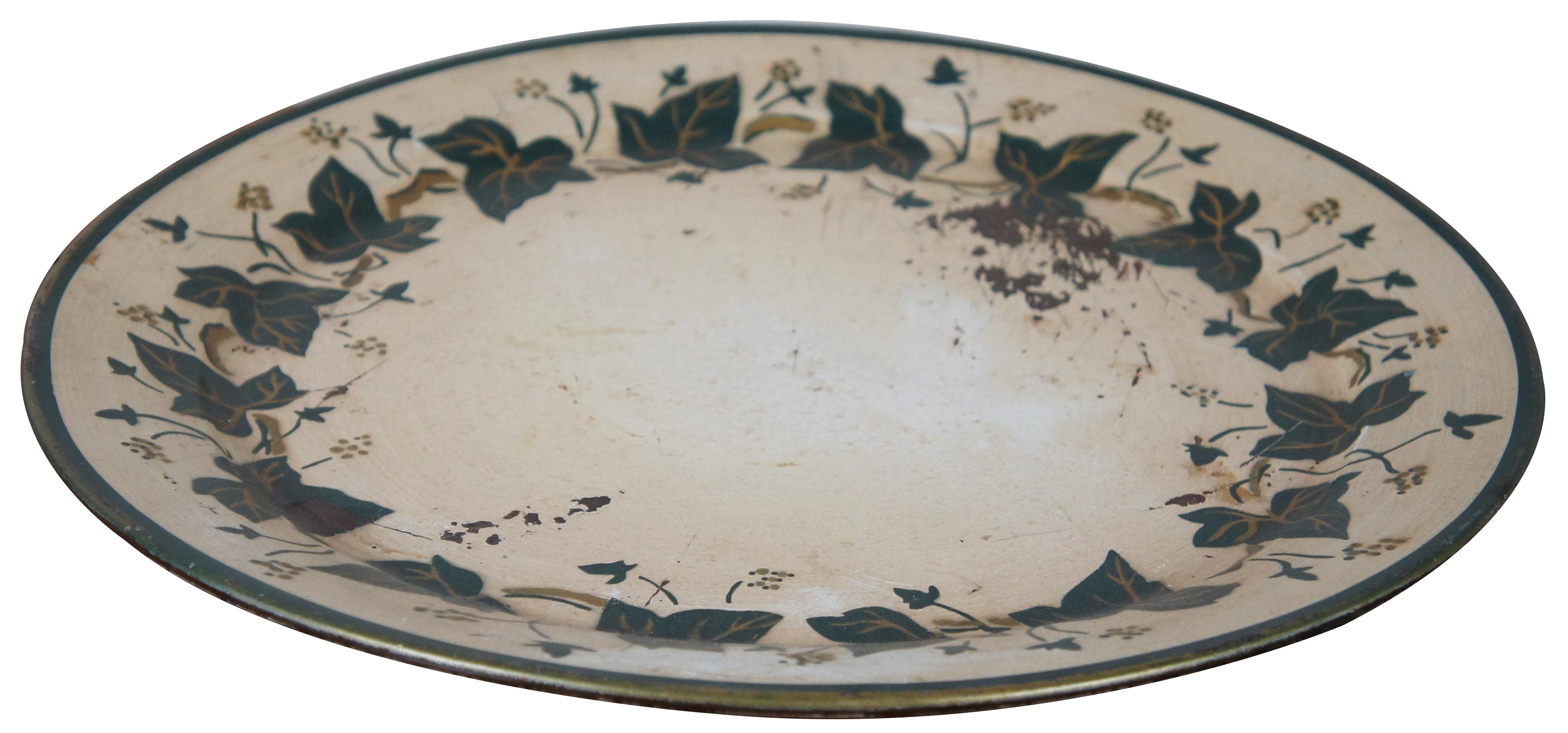 Vintage mid-20th century round metal tray painted in white with a green edges and border of vining ivy leaves.