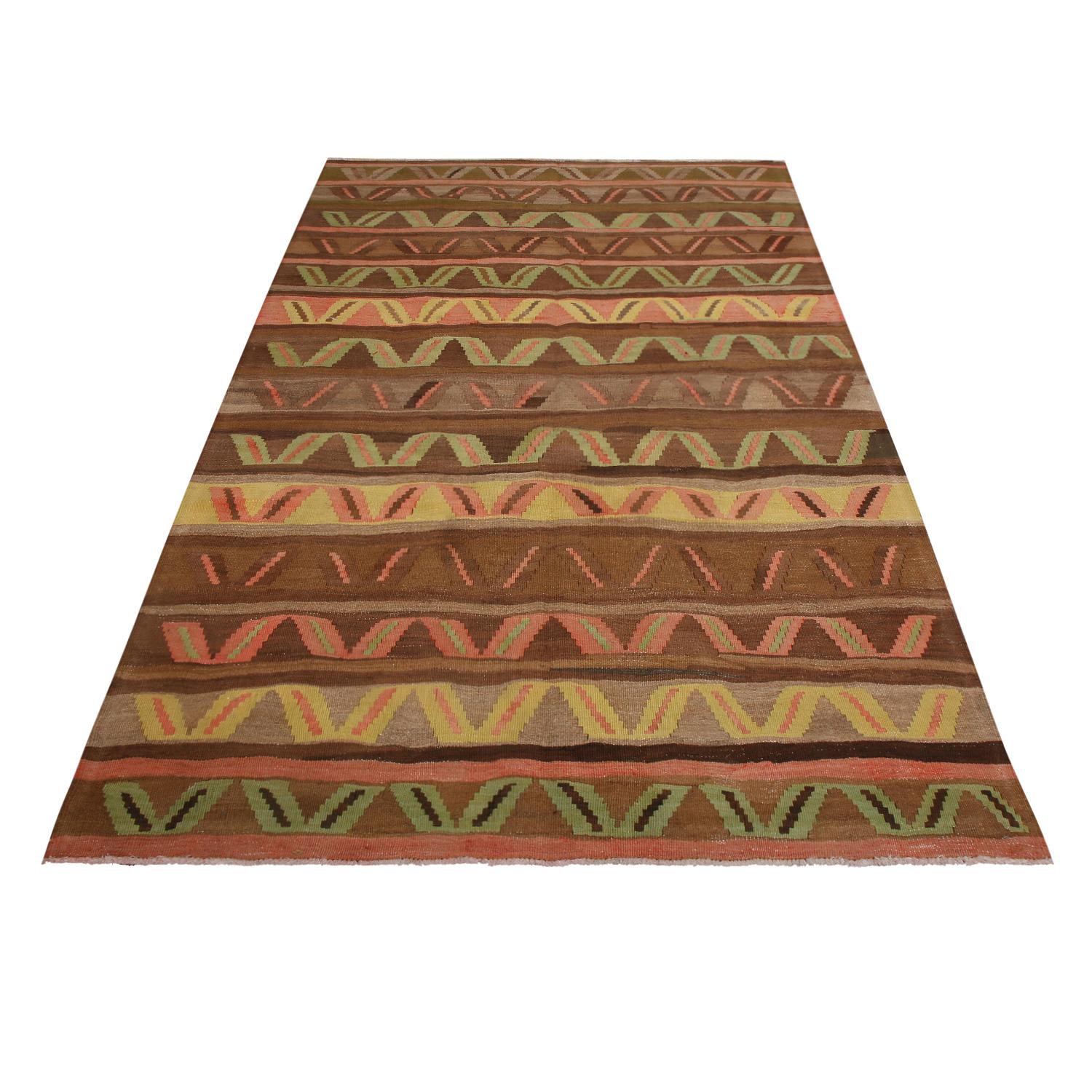 flat-woven in Turkey originating between 1950-1960, this vintage midcentury wool Kilim hails from the city of Kars, enjoying subtly abrashed variations of brown with lively accents of green, yellow, and pink-red; a marriage of earth tones and bright