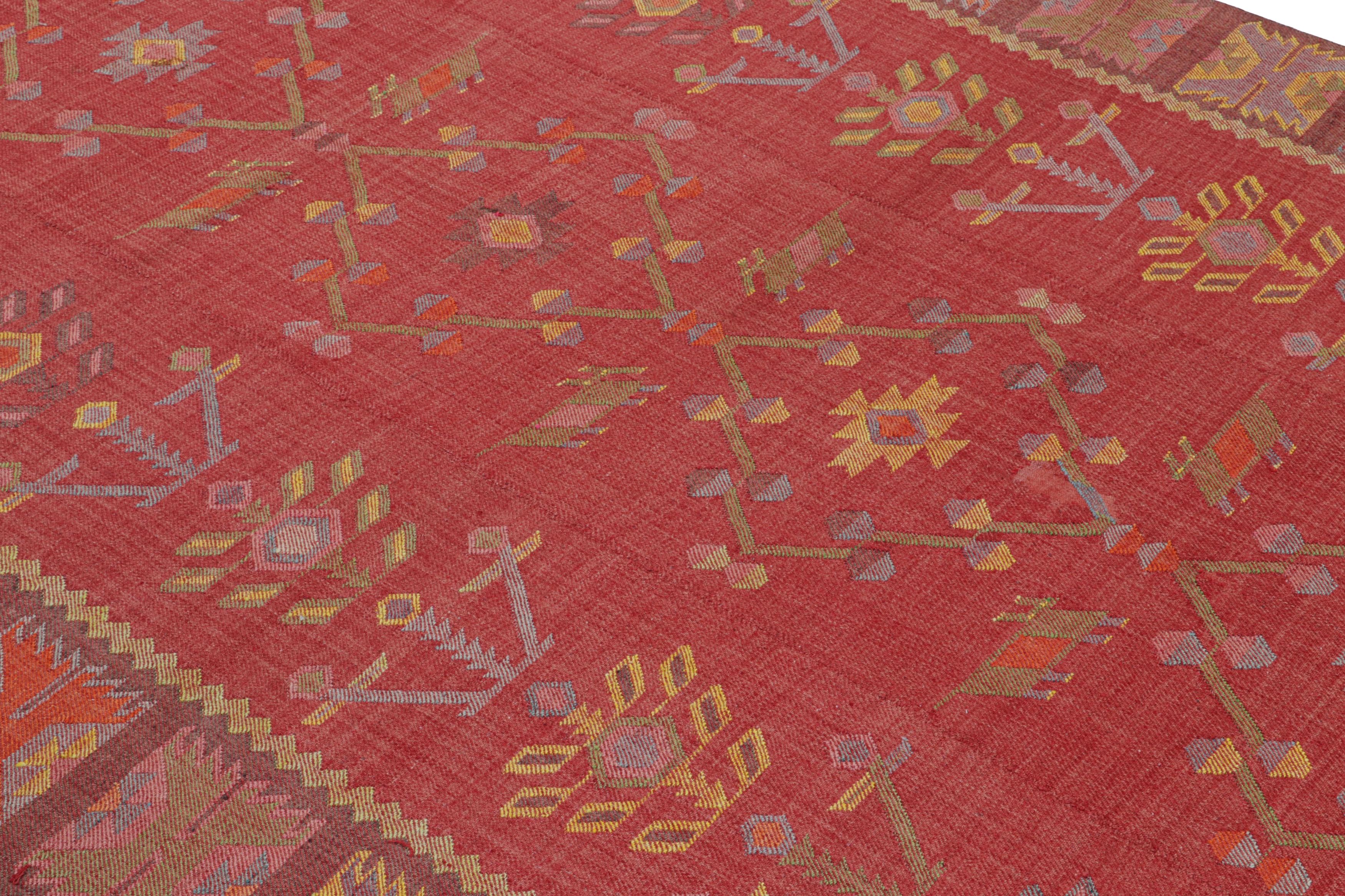 Handwoven in a wool flat-weave originating from Turkey circa 1950-1960, this vintage Kilim rug connotes a midcentury Kilim origin in very discerning, warm shades of raspberry and coral red complementing the foreground play of golden-yellow and blue.