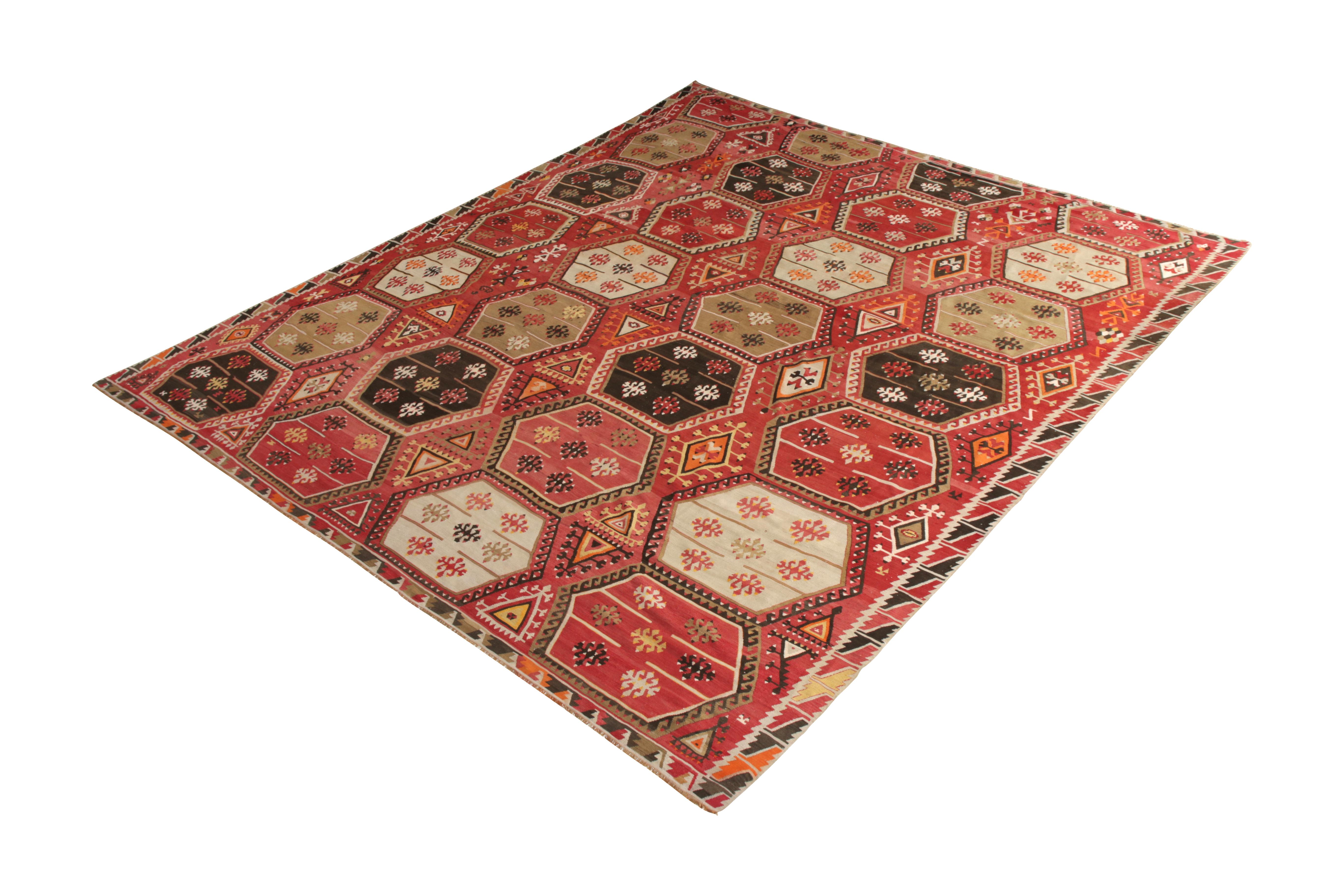 Handmade in flat-woven wool originating from Turkey circa 1950-1960, this midcentury rug is a vintage Kilim rug of a unique graph and distinctive pink-red colorway, complementing bolder blue, green, and black hues in the rows of geometric all-over