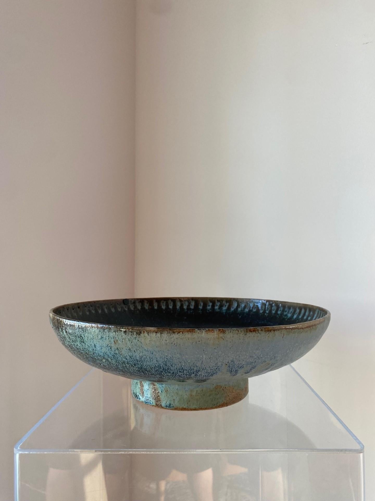 Beautiful vintage large ceramic bowl.  This incredible piece is unique and sculptural.  Conceived from its pedestal base, the bowl extends to a diameter of 13.25”.  The bowl presents an incised design that runs thru the rim of the bowl as well as
