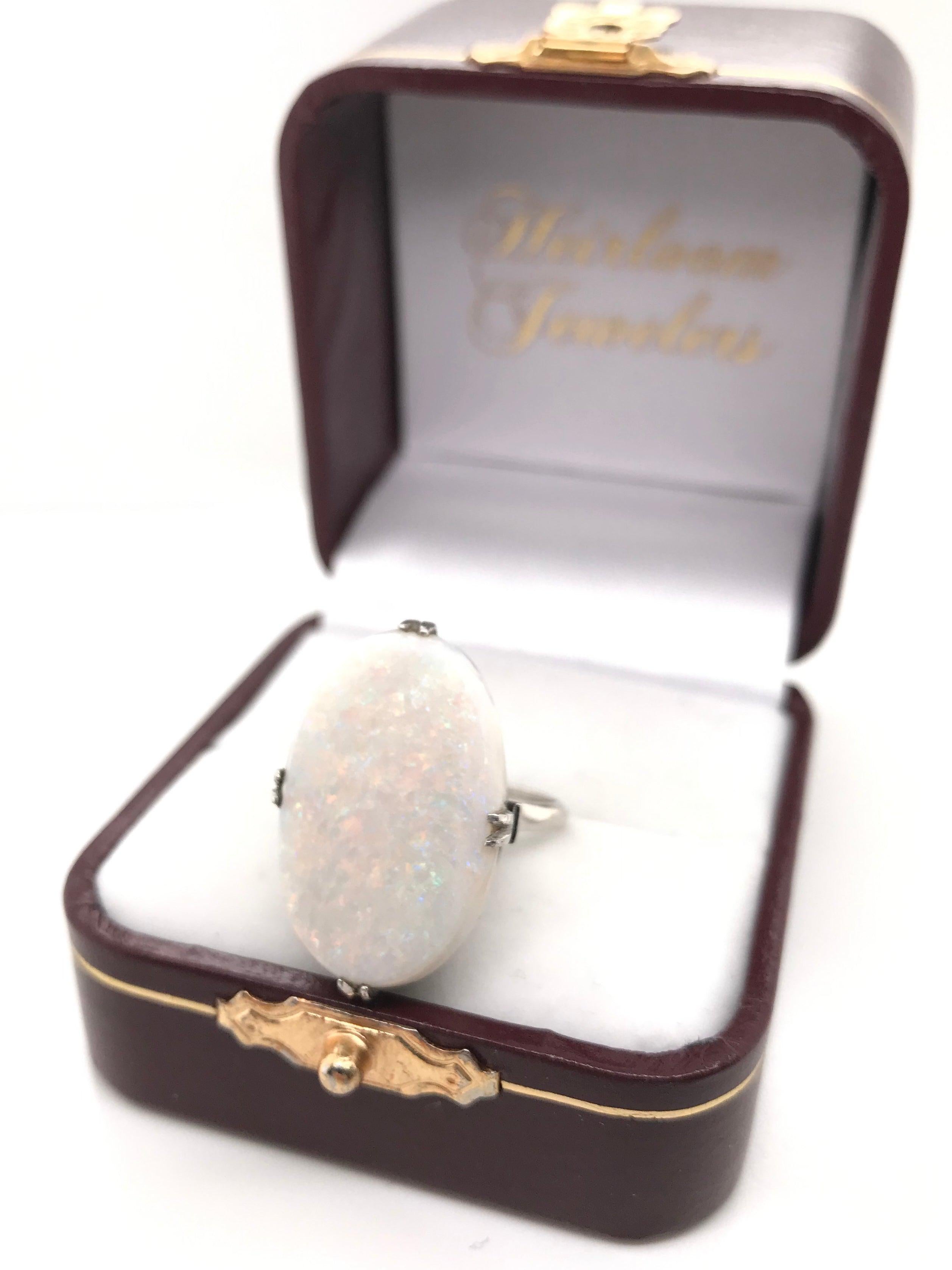 This Retro era cocktail ring was crafted sometime during the Mid Century design period (1940-1960). The ring features a large white opal measuring approximately 9.50 carats. The white opal features subtle yet satisfactory play of color and fire. The