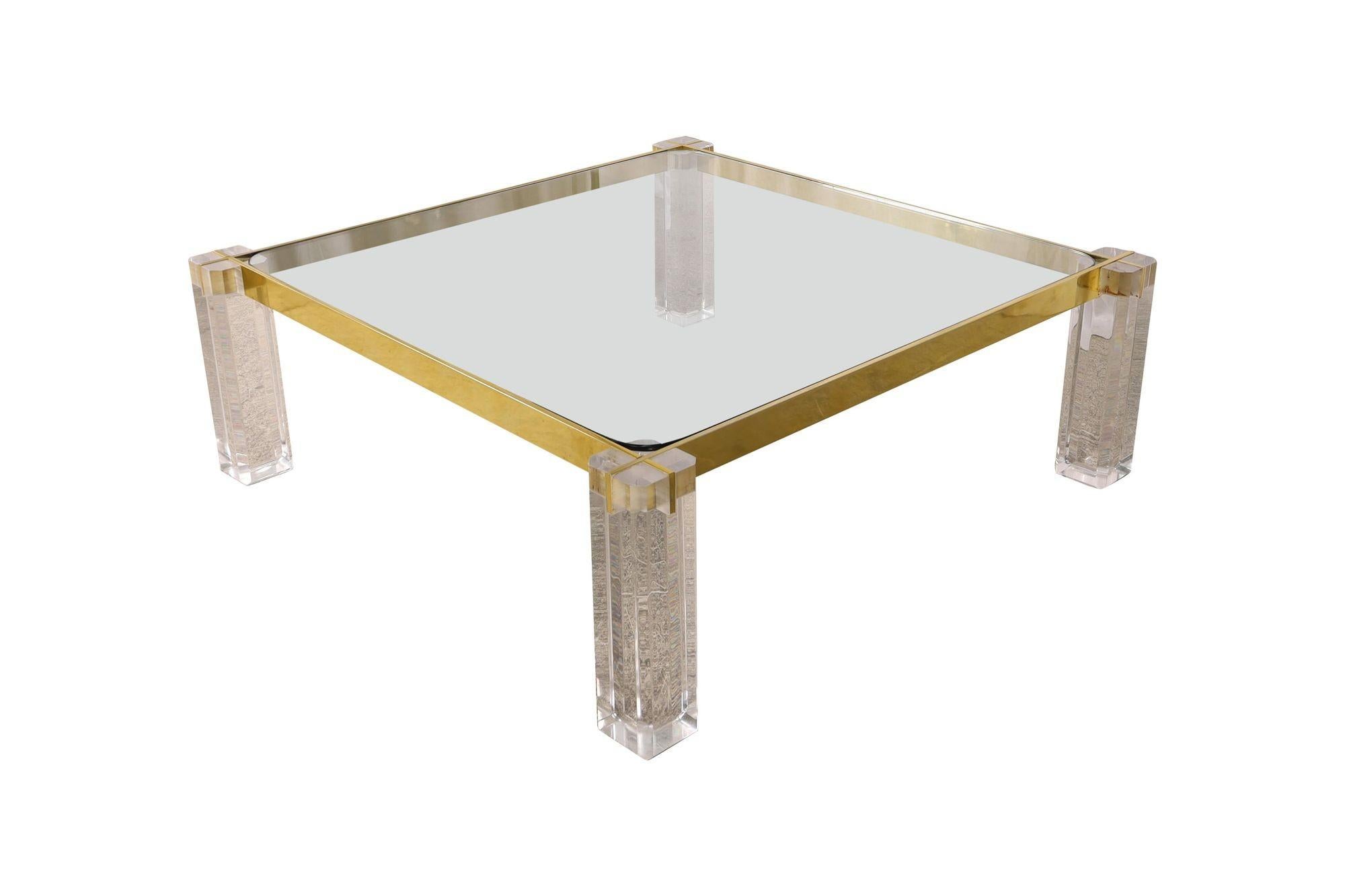 Vintage Mid-Century squared coffee table made in USA in the 1970s. Its standout feature lies in the transparent lucite legs, and a sleek brass frame surrounding the table. It is protected by a thick glass top.
Dimensions:
15