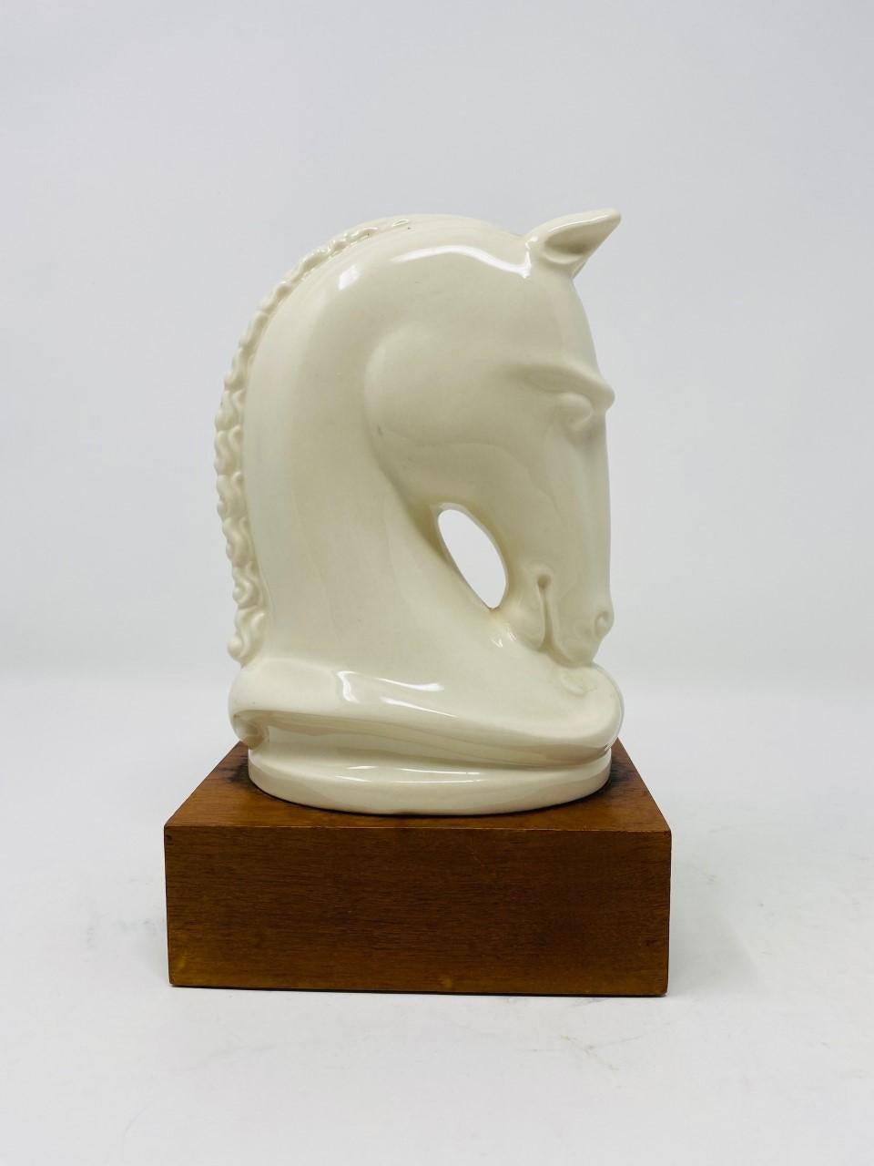 Beautifully rendered sculpture in porcelain. This piece is expressive and forcefully rendered in glazed porcelain. As a subject, this horse bust is majestically rendered demanding attention as it sits on a felted wooden base. Classic, beautiful