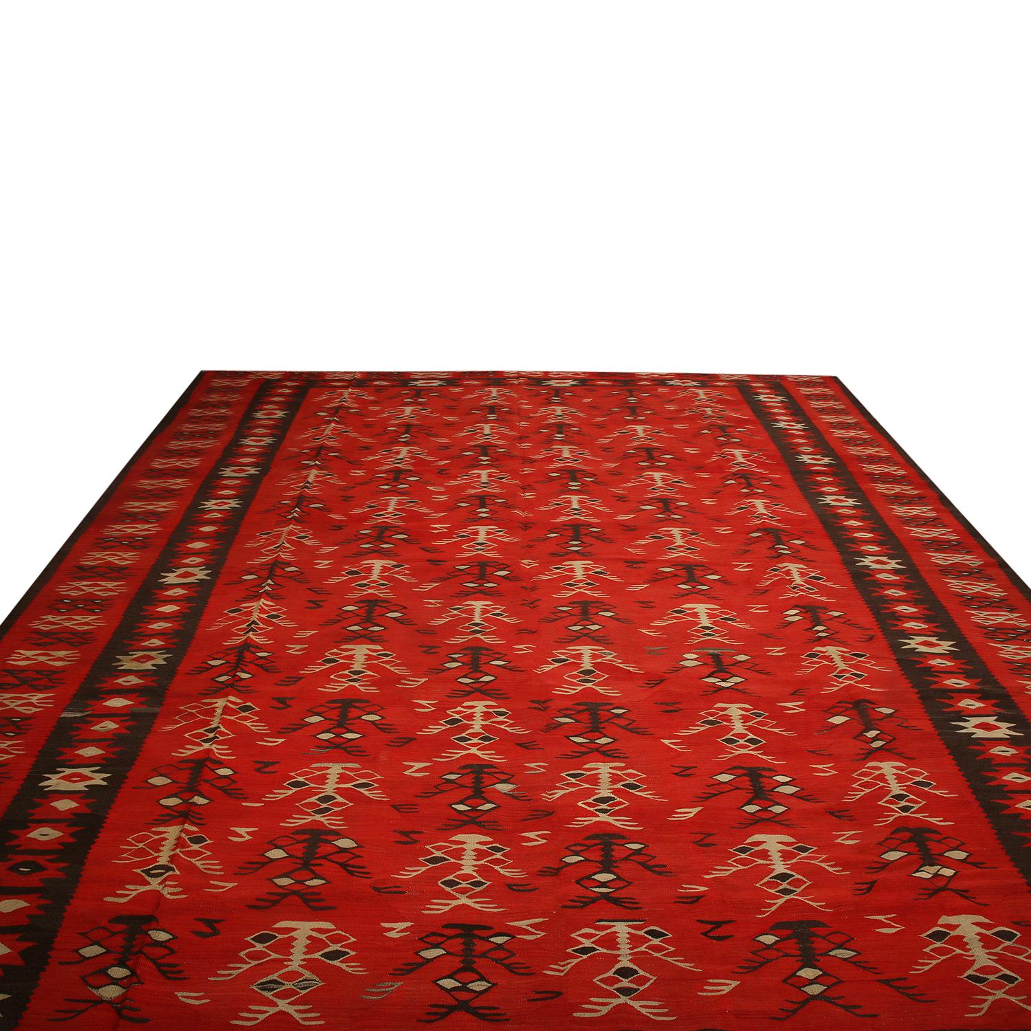 Handwoven in wool circa 1950-1960, a vintage tribal Kilim rug believed to hail from a rare Macedonian provenance. The rare 10x12 large size, distinctive geometry, and play of this particular red with rich brown and beige hues may connote origins in