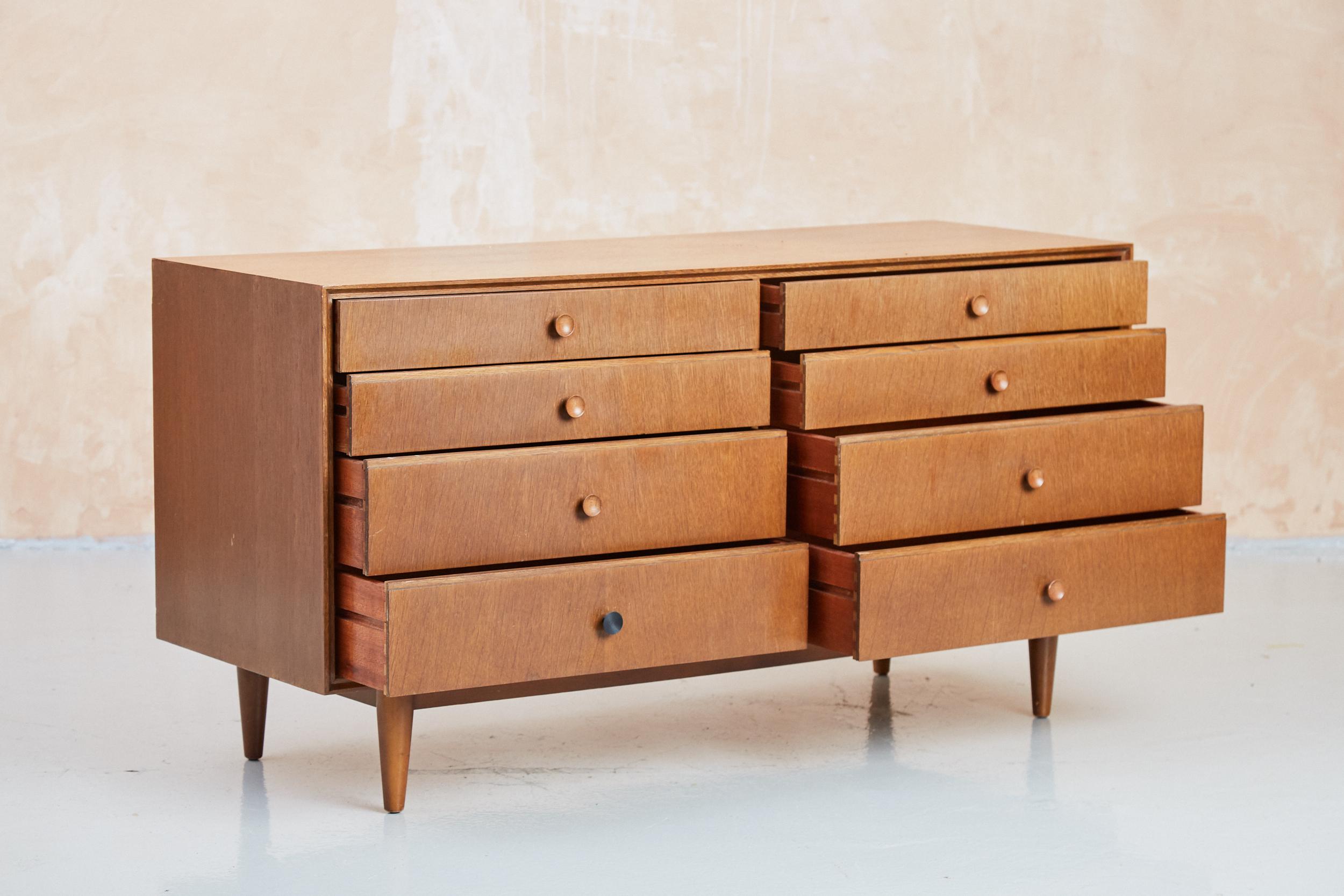 A rare vintage Meredew chest of 8 drawers, manufactured in the 1960s. Finished in dark oak, with solid oak conical handles, an iconic feature of Meredew from the mid century. The piece is a very comfortable size, between a sideboard and a chest of