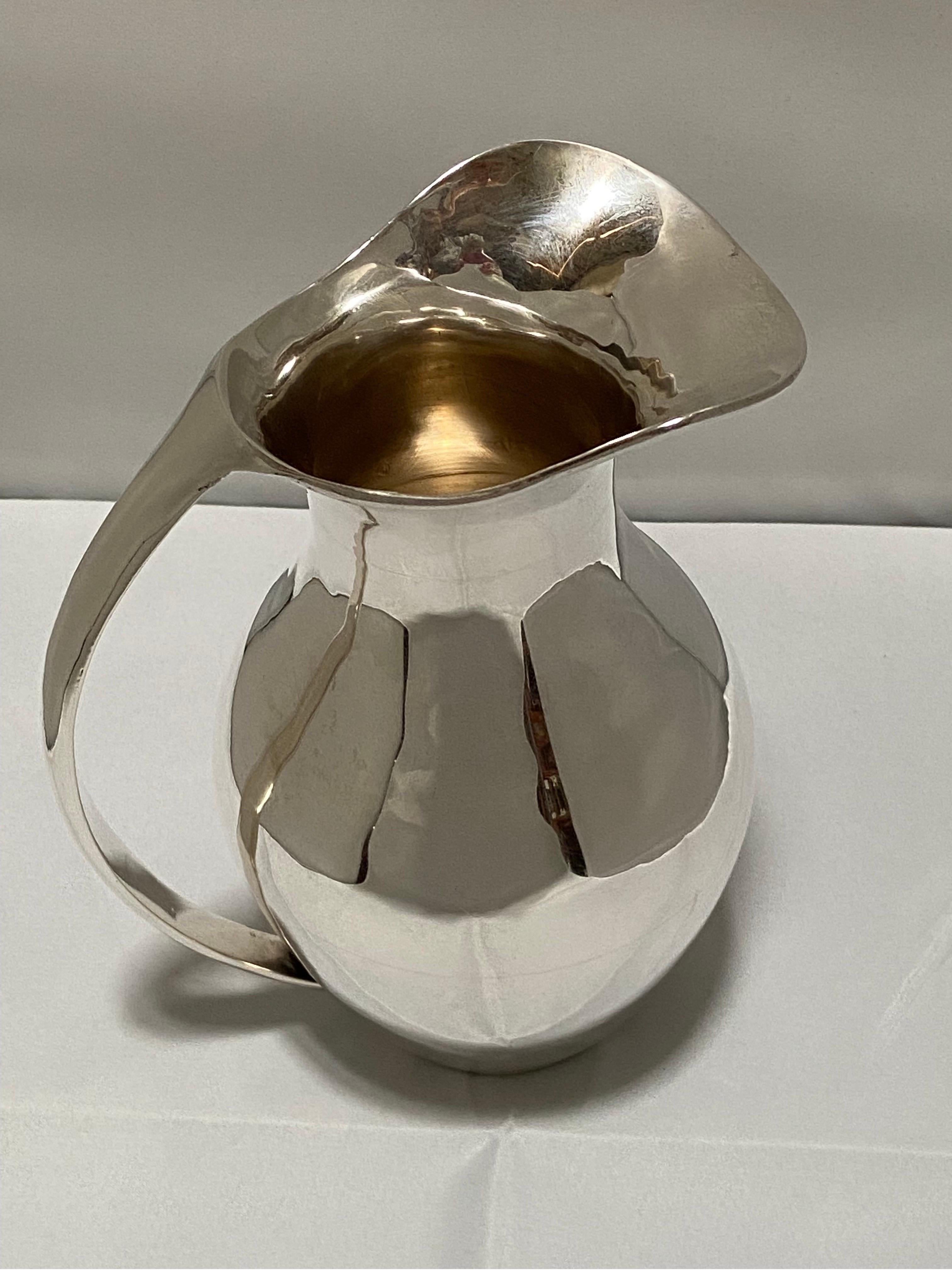 A vintage, Mid-Century Modern Mexican sterling silver pitcher by the maker, C. Zurita. With a nod to the eponymous design firm of Georg Jensen, this sterling silver ewer has a gorgeous modernist style with flowing lines and wonderful scale. Marked