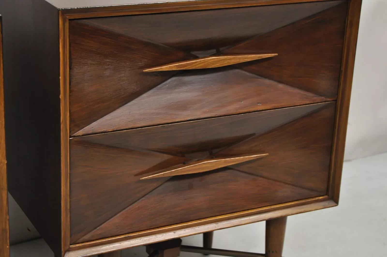 Vintage Mid Century Modern 3D Diamond Facade Walnuss Nachttische - ein Paar. Das Möbelstück verfügt über Querstreben mit Messingakzenten, je zwei Schubladen, geschnitzte Holzgriffe und klare modernistische Linien. Circa Mitte des 20. Jahrhunderts.
