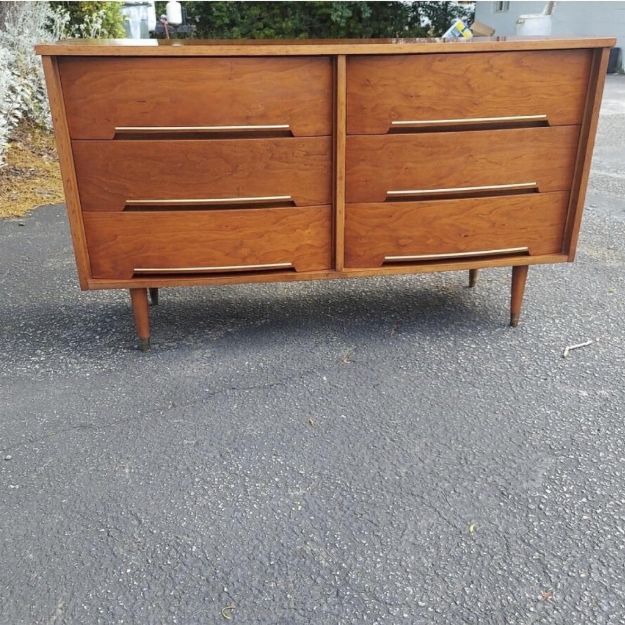 This vintage modern sturdy walnut dresser features brass inlays and inset drawer pulls. Its straightforward design and tapered brass-capped legs are sure to fit in any modern home. 
Measurements:
Side to side 54, front to back 18, floor to top 31.
