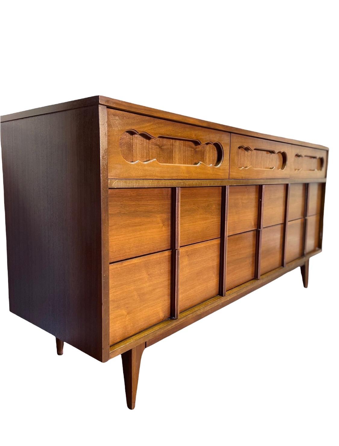 An elegant Mid-Century Modern nine drawer dresser. The dresser features gorgeous walnut wood grain and sleek mid-century design. It offers ample room for storage, with nine dovetailed drawers and original.

Dimensions: 62 W 18 D 43 H.

      