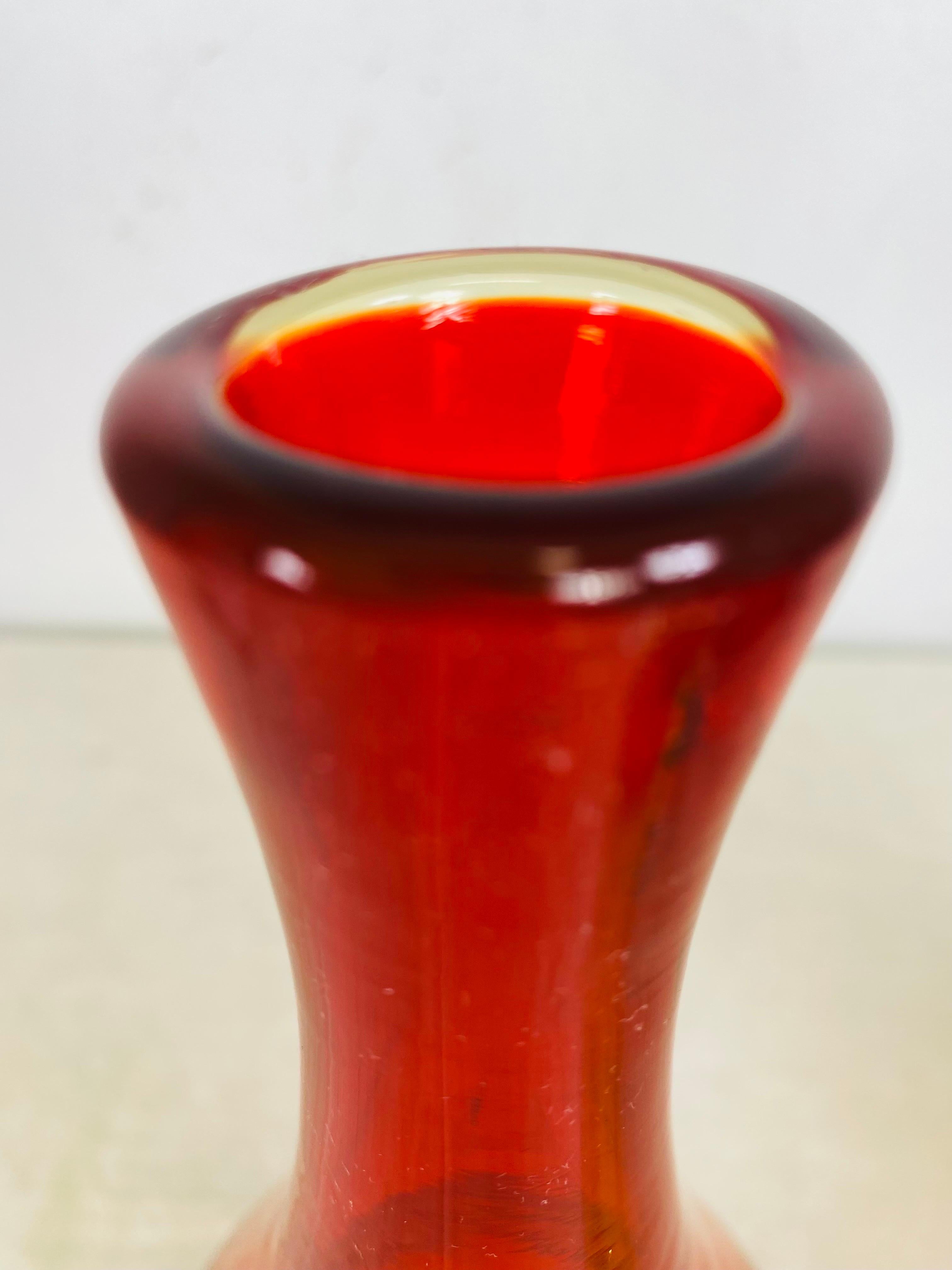This is a midcentury, modern hand blown ambarina bud vase by Wayne Husted for Blenko. Wayne Husted was the Director of design at the Blenko Glass company in Milton, West Virginia. This slender elegant hand blown vase has an amber tone at the base