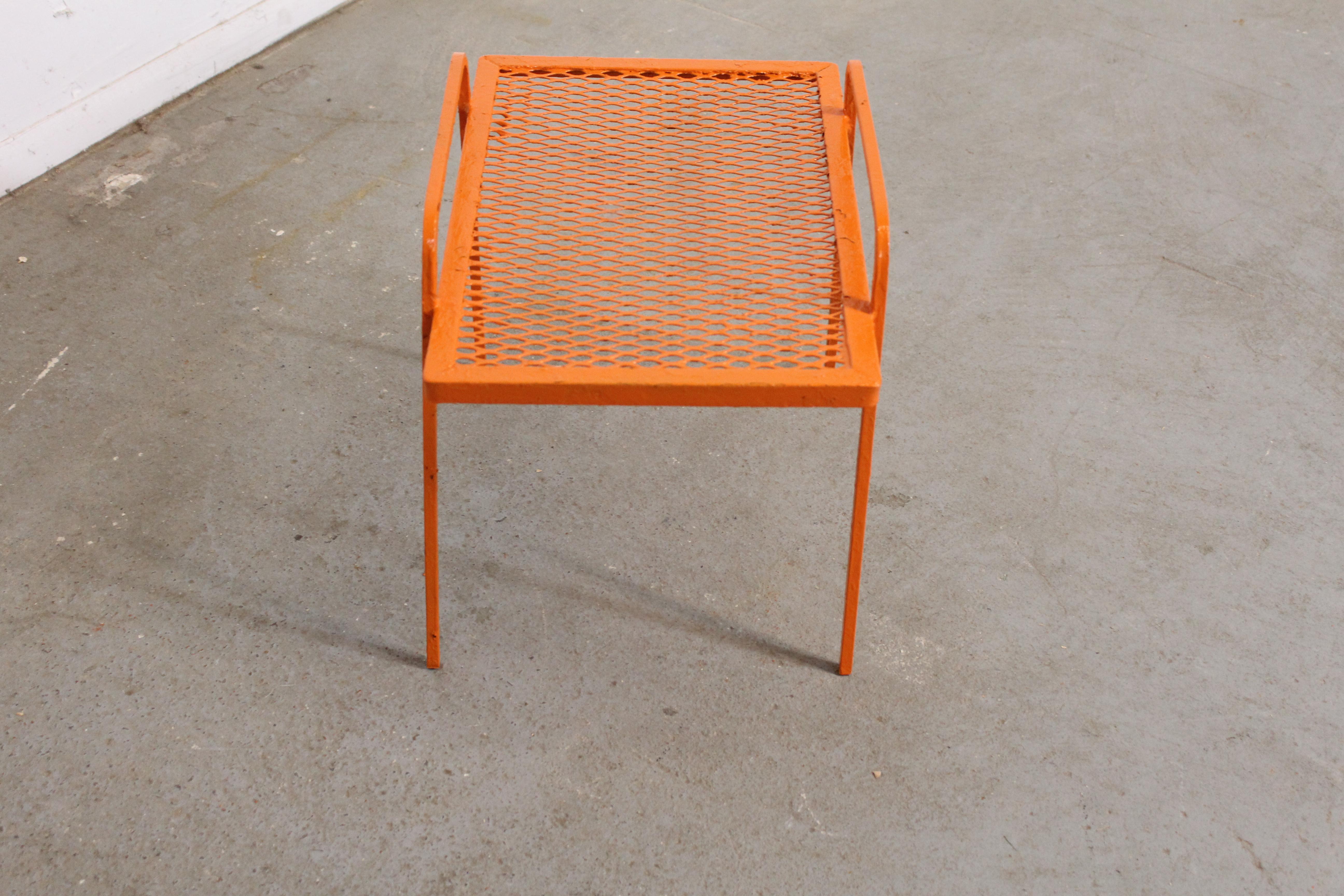 Offered is a vintage Mid-Century Modern atomic orange metal end table, circa 1960's. This piece is made of welded steel and features gracefully styled legs and a mesh top. It is in good condition considering its age with minor age wear (surface