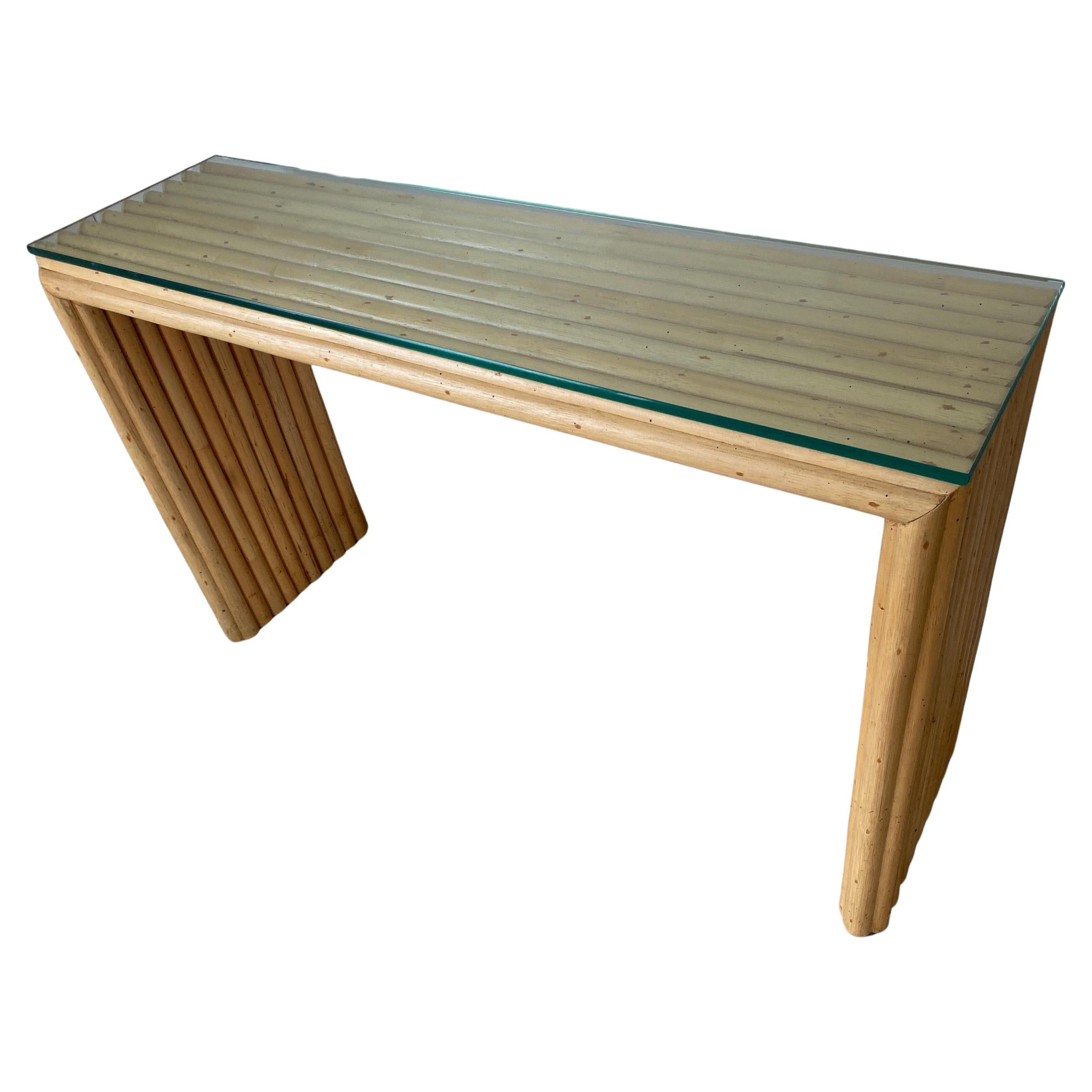 La table console de canapé en bambou avec plateau en verre, icône de la modernité du milieu du siècle, présente des lignes organiques simples et épurées. La table a un bord en forme de cascade.
Associez-le aux piédestaux demi-ronds en bambou ou à